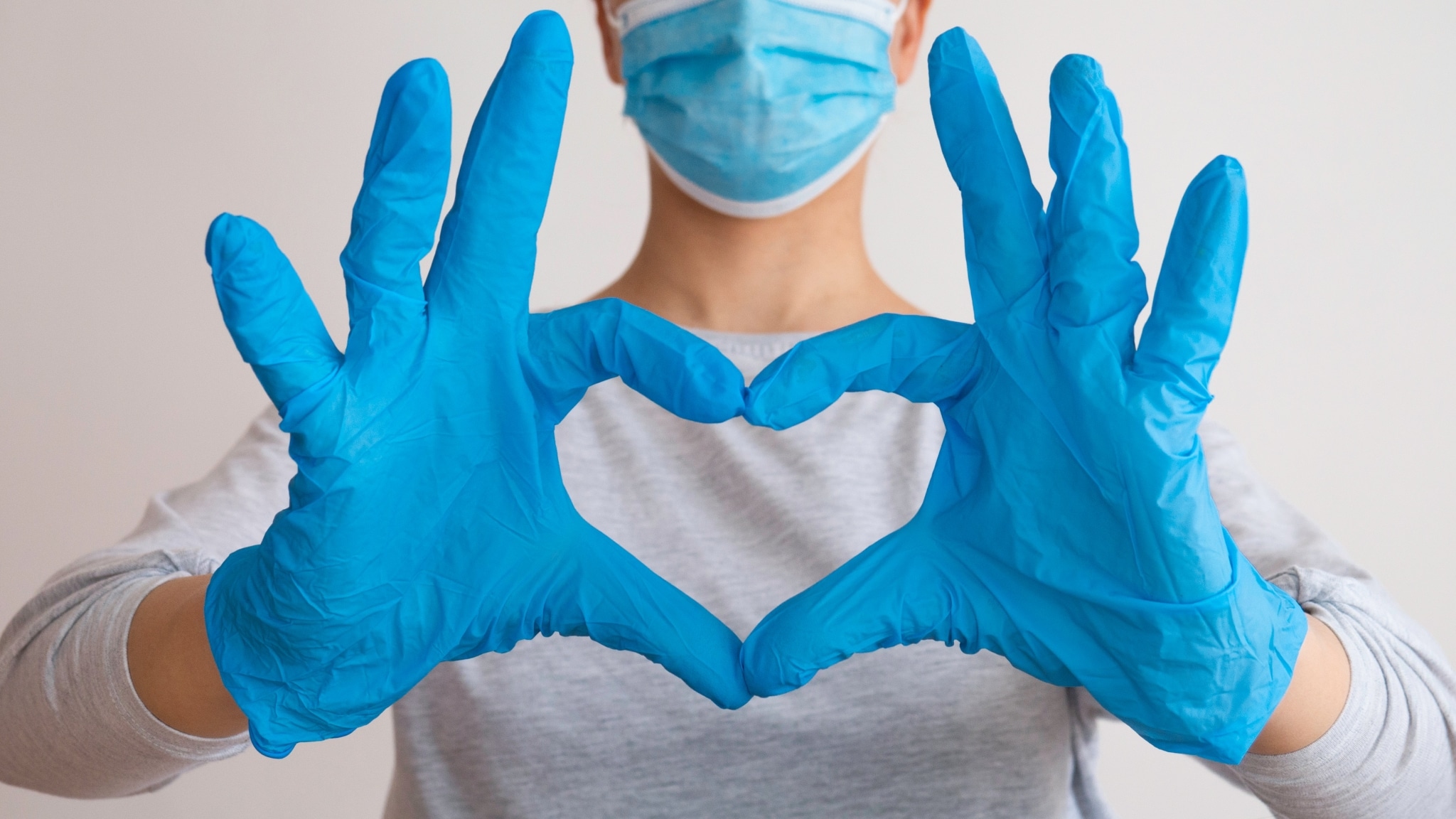 Woman in scrubs forming a heart with her hands