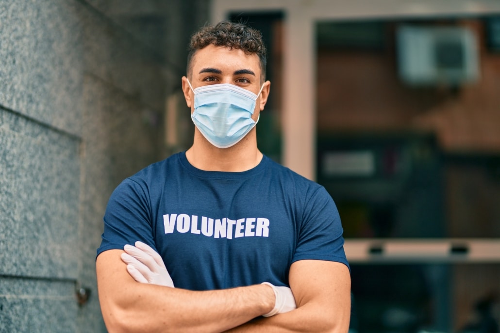 Young hispanic volunteer man with arms crossed