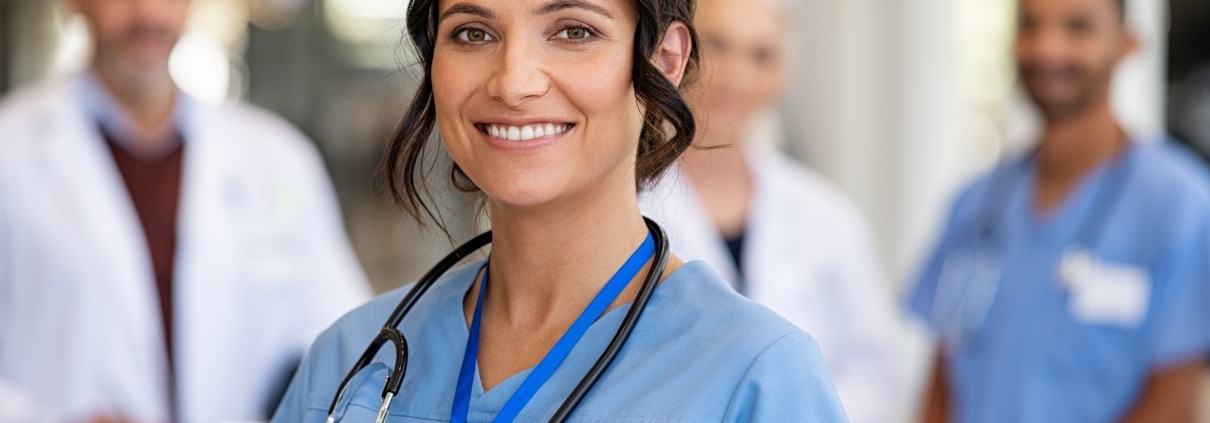 Smiling nurse with a team behind her