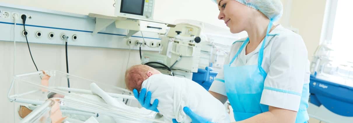 Young female nurse holding a newborn baby