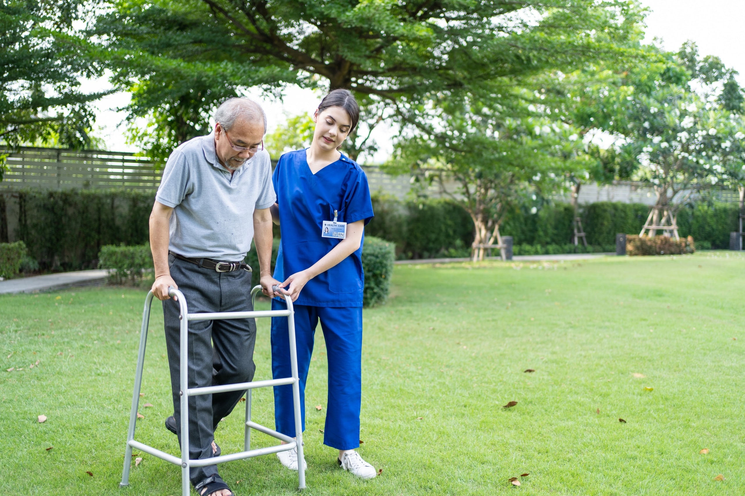 Asian caregiver assists elderly patient outside