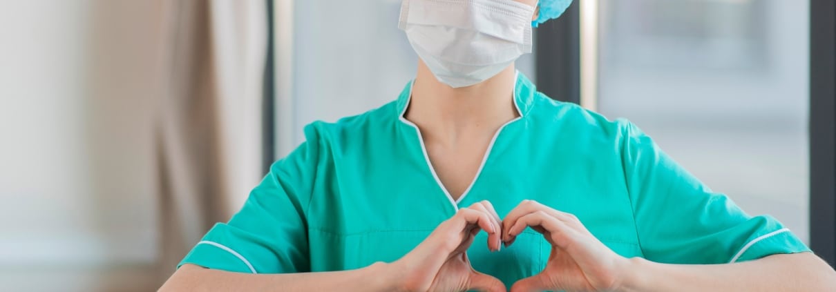 Masked nurse forming a heart with her hands