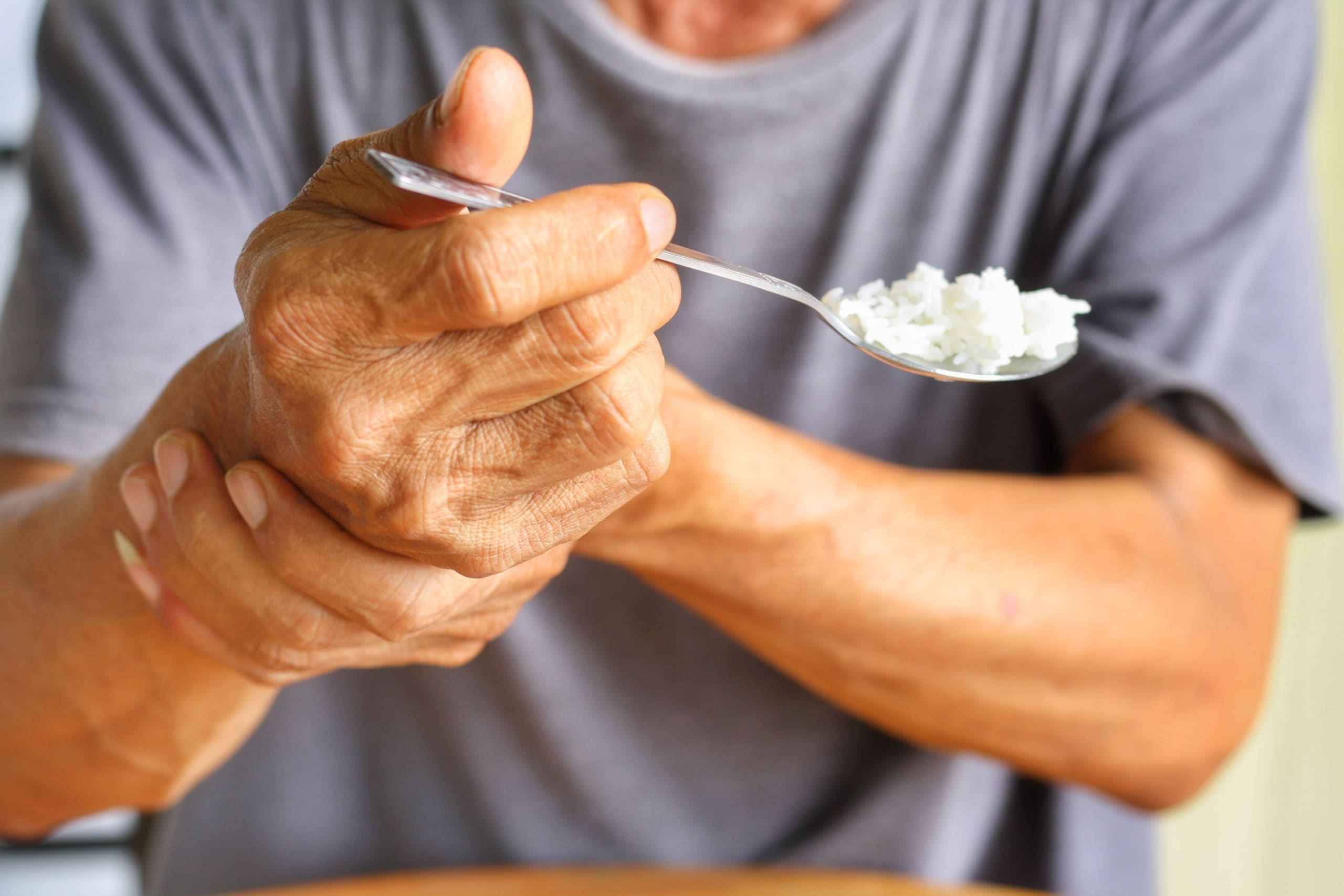 Man with Parkinson's disease holding a spoon of rice