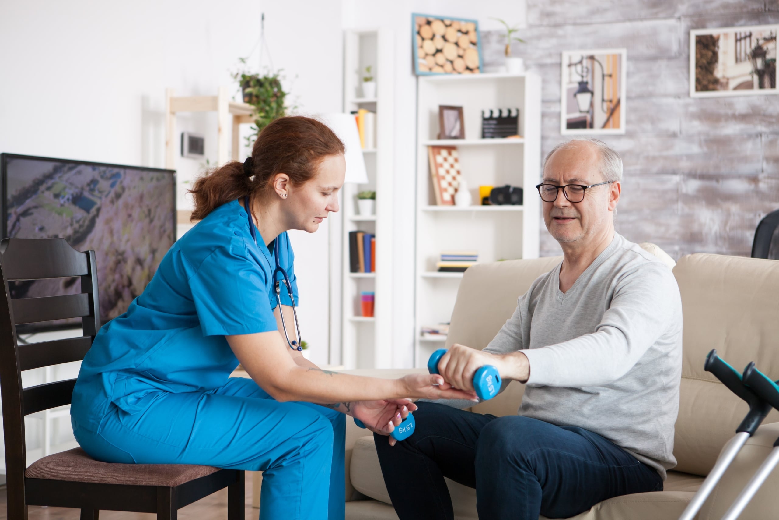 Medical worker helping a patient do physiotherapy in his home
