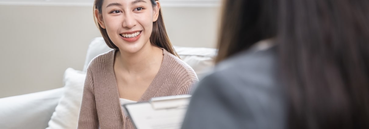 Smiling young woman on a couch next to a medical professional