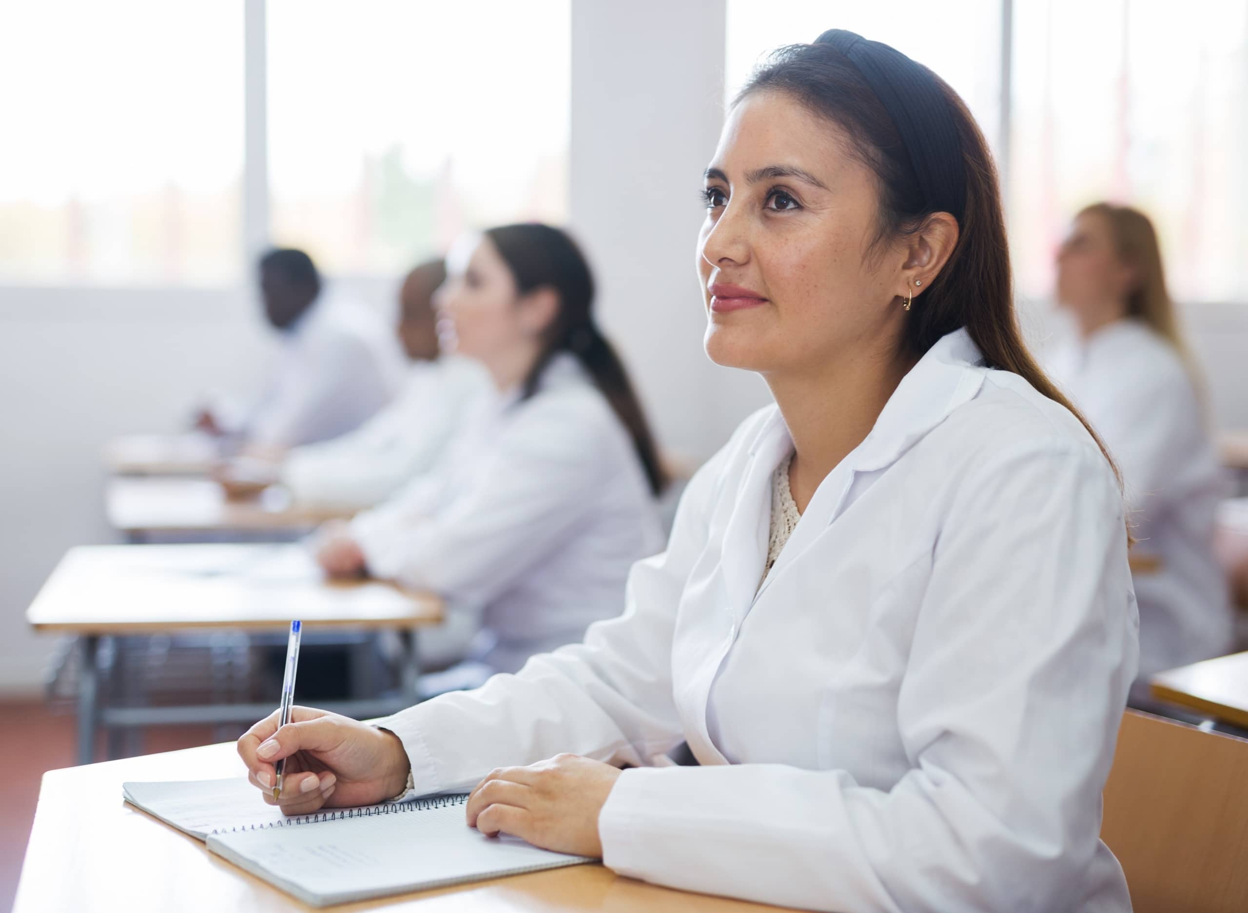 Latin woman sitting at a desk during a medical lecture
