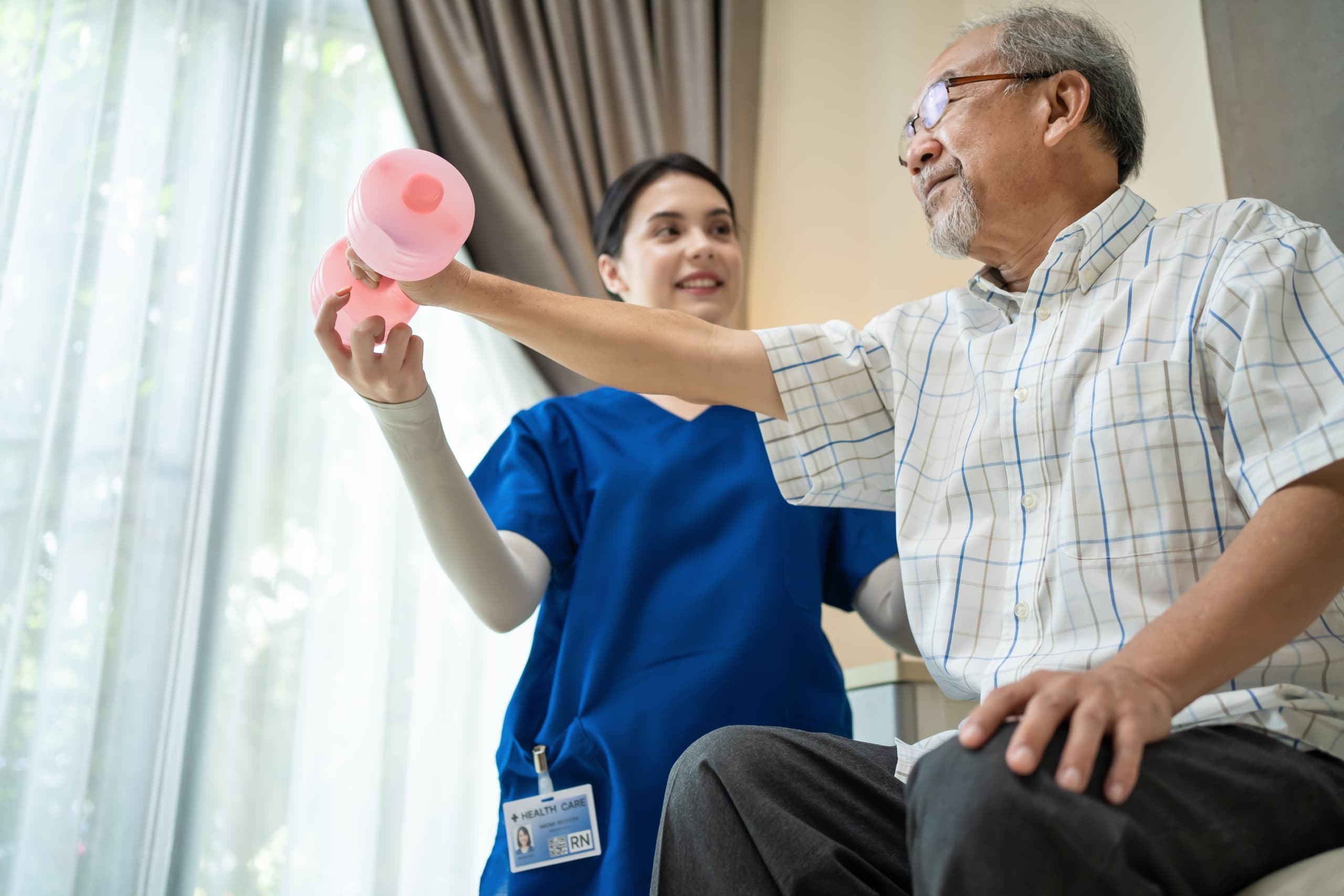 Medical professional assisting an elderly man with physical therapy