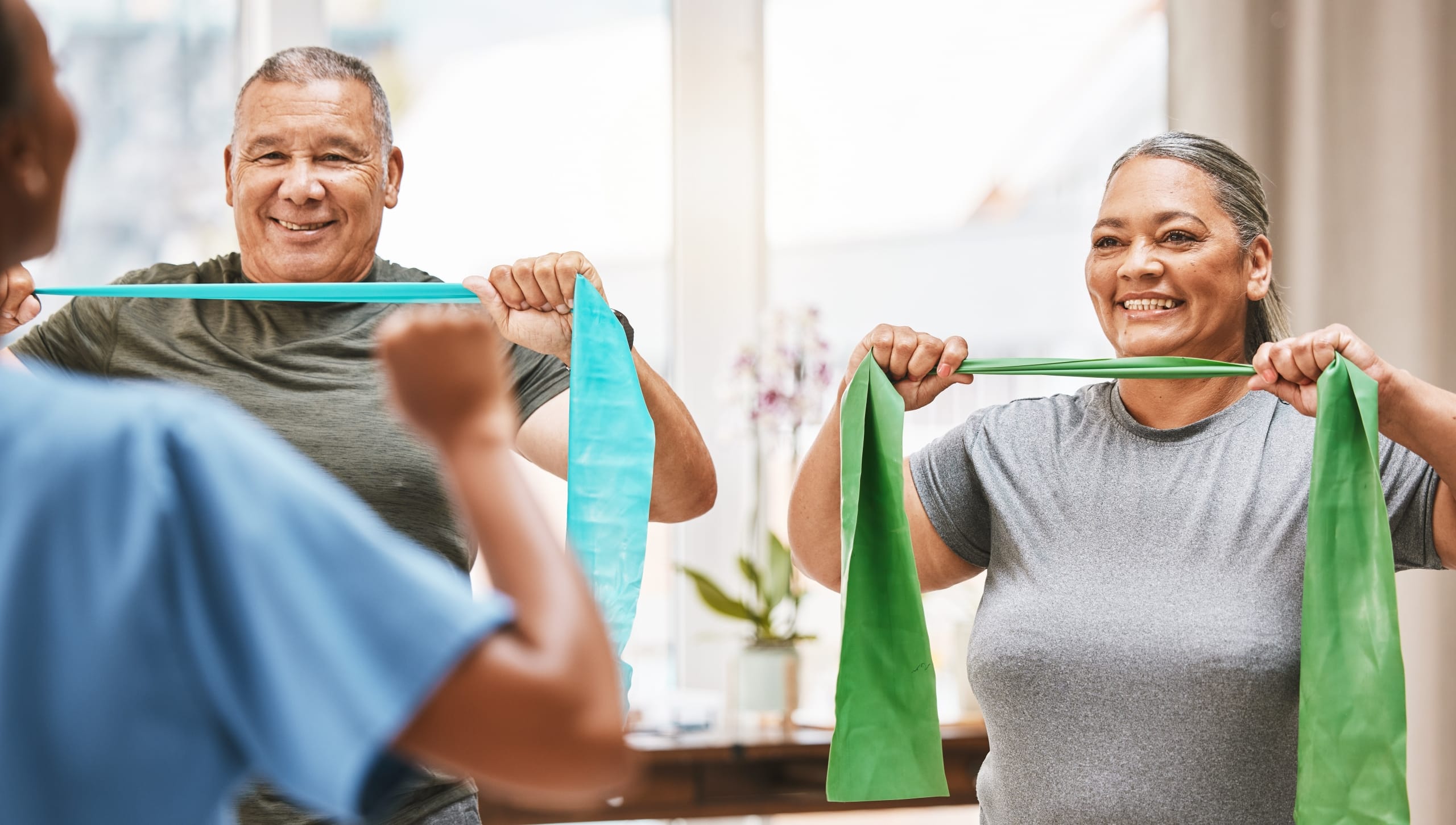 Two elderly people using stretch bands in physical therapy