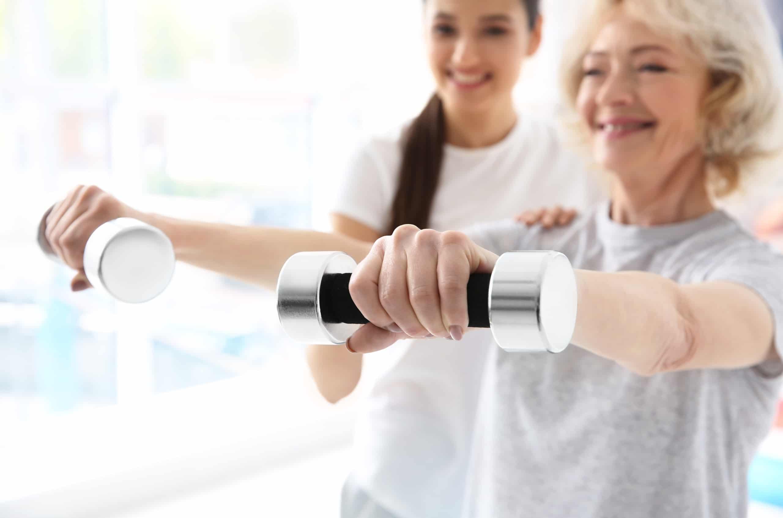 Close up of an elderly woman using weights in physical therapy