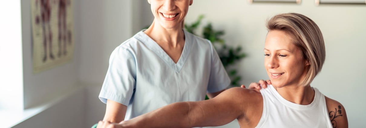 Physical Therapist Assistant helping a female patient lift weights