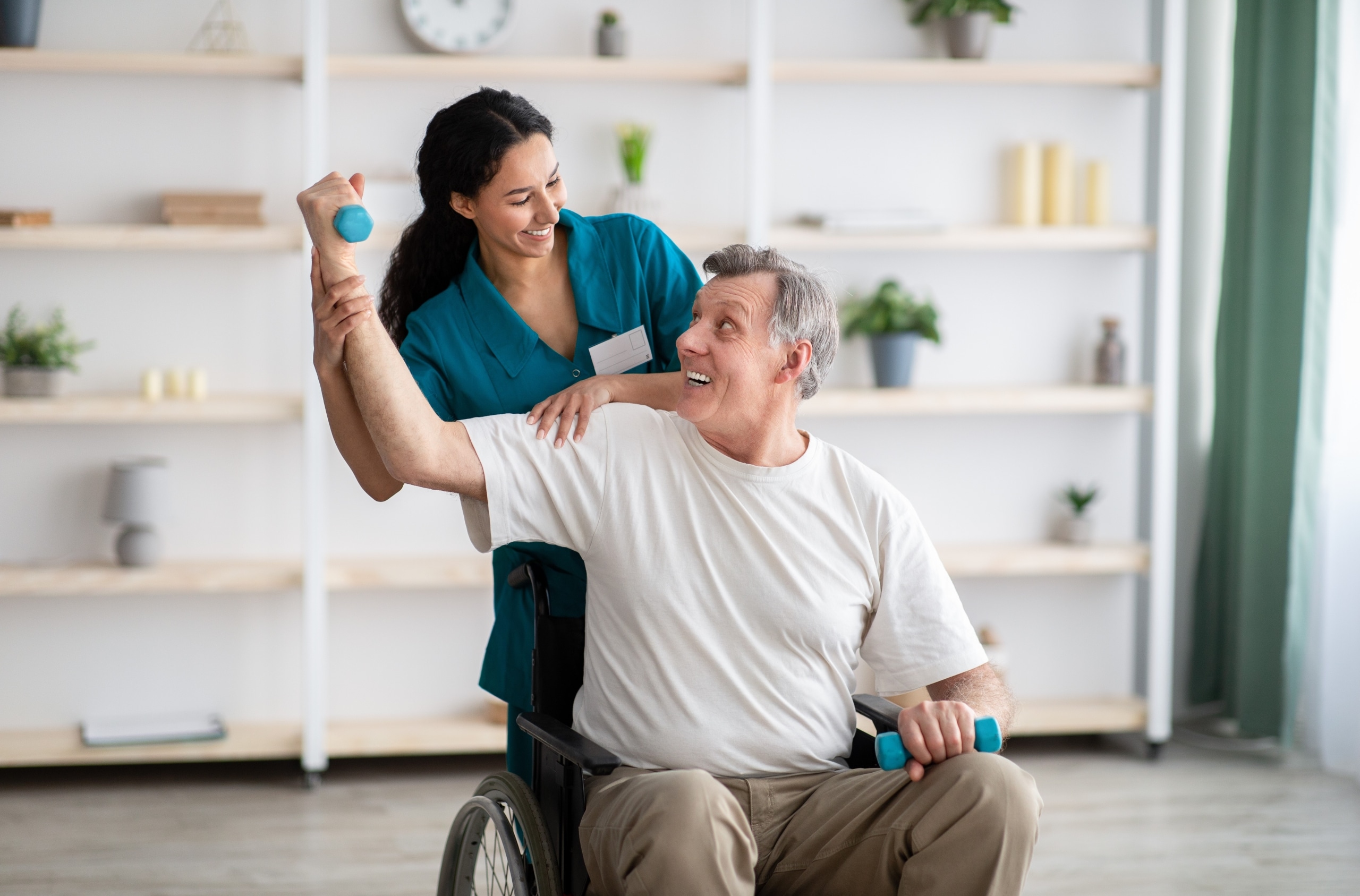 Physical Therapist Assistant helping a man in a wheelchair lift weights