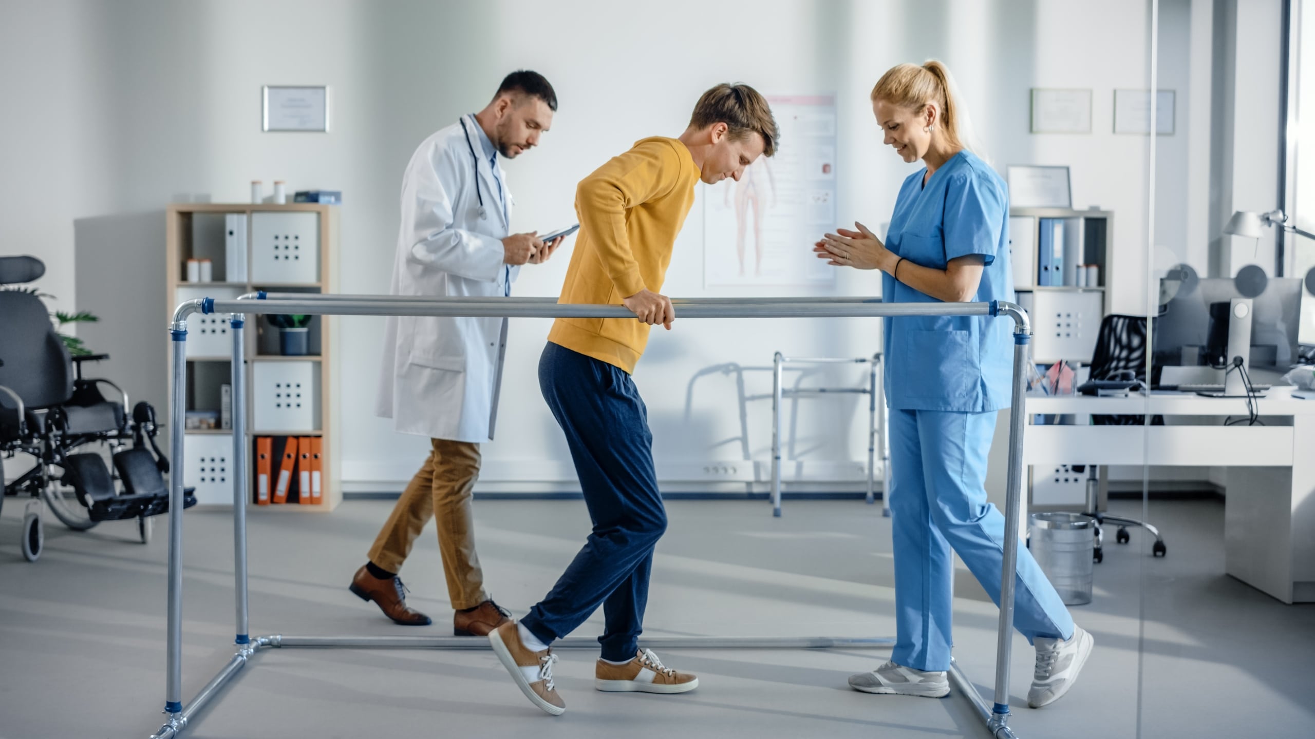 Physical therapy team helping a male patient improve his gait