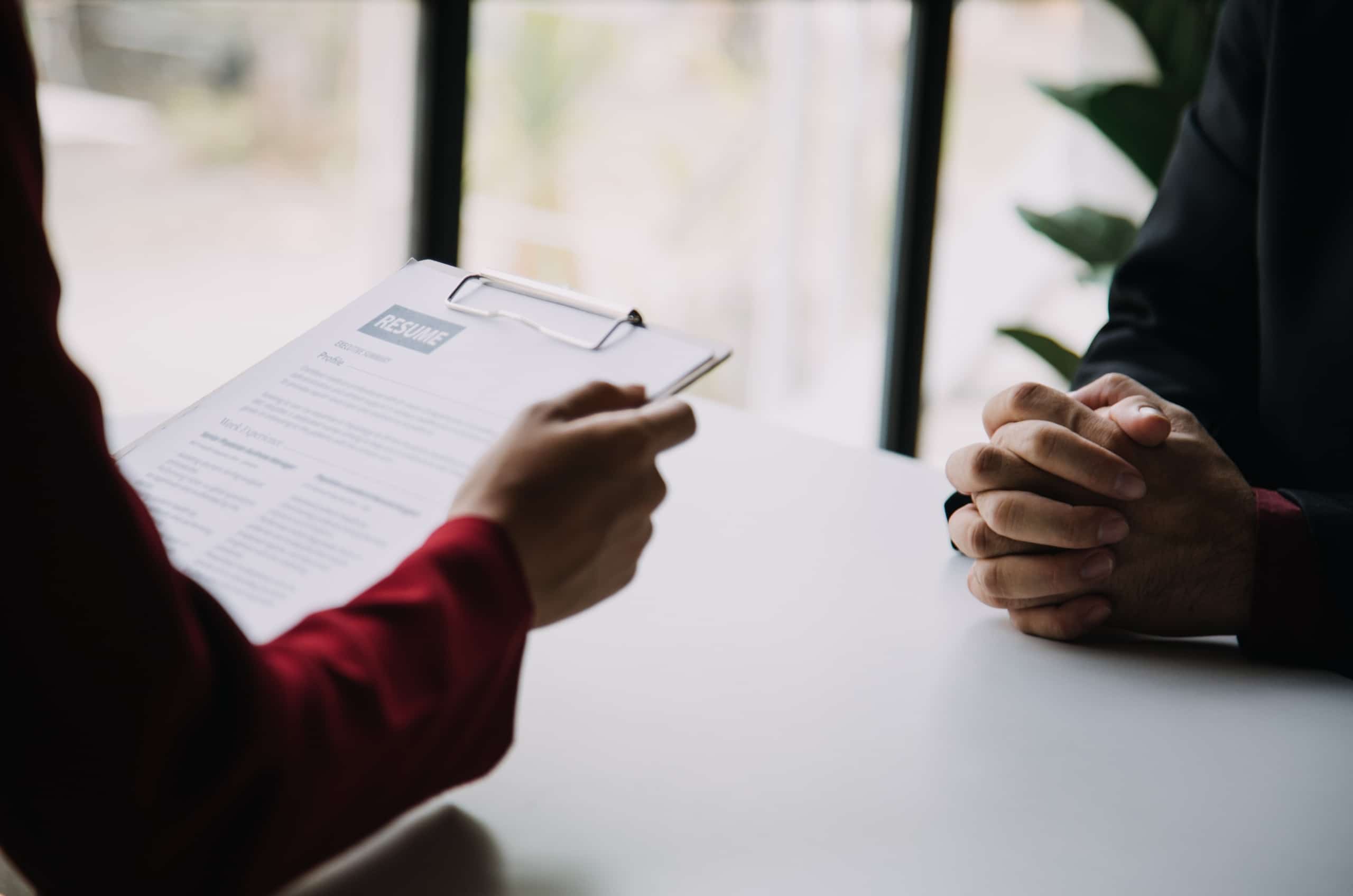 Two people in an interview with a resume on a clipboard