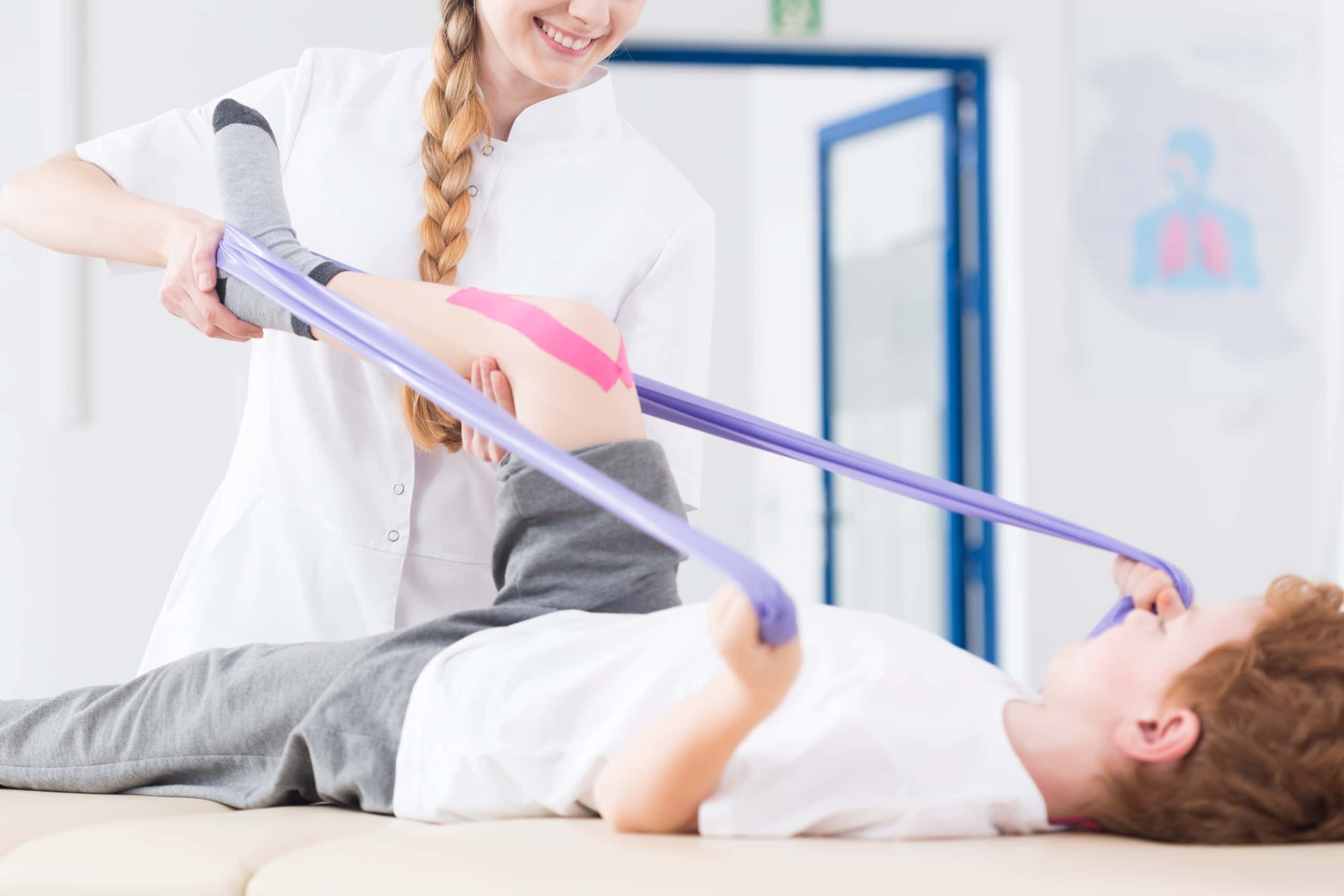 Physical Therapist Assistant helping a pediatric patient use exercise bands