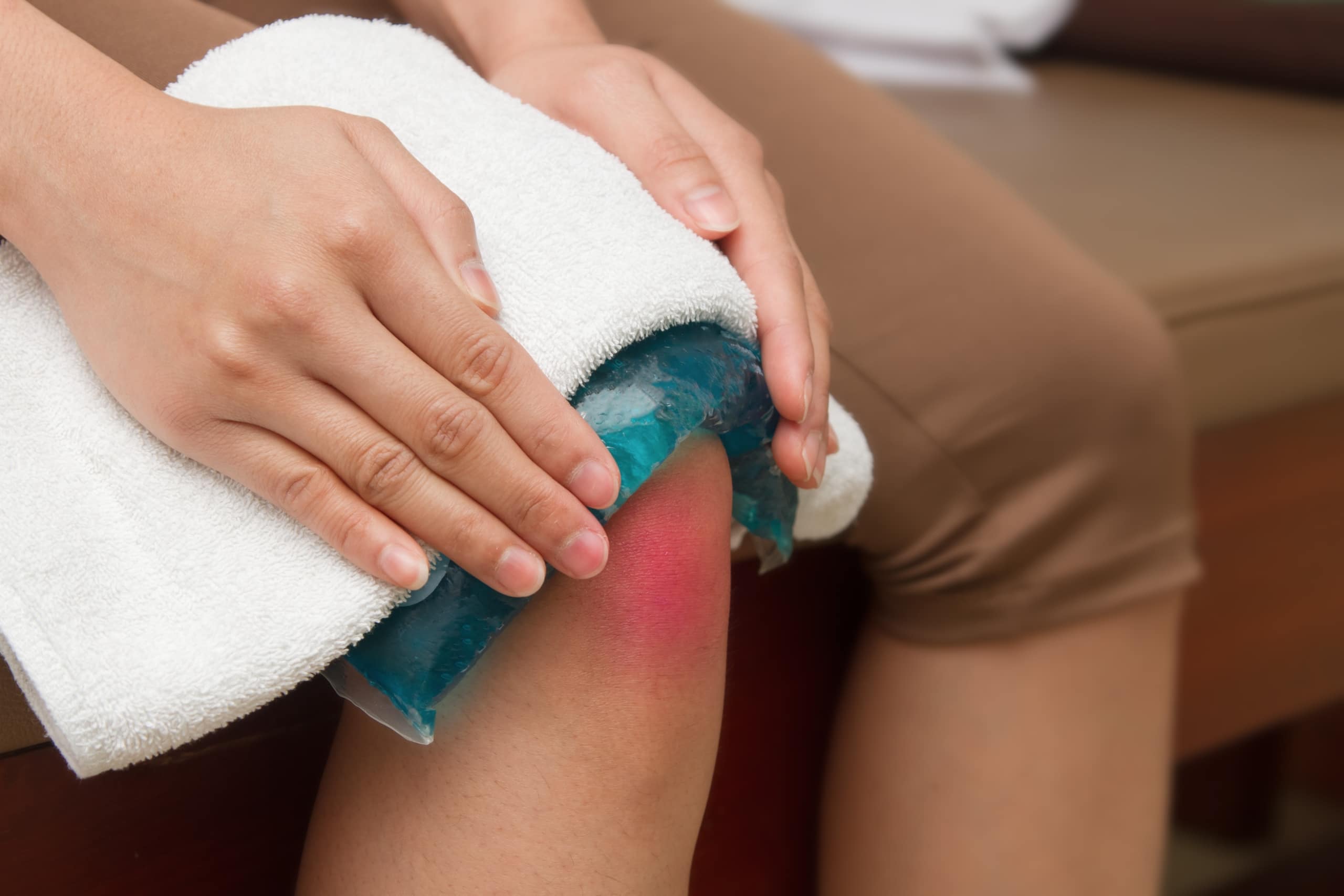 A person applying a cold compress to their knee