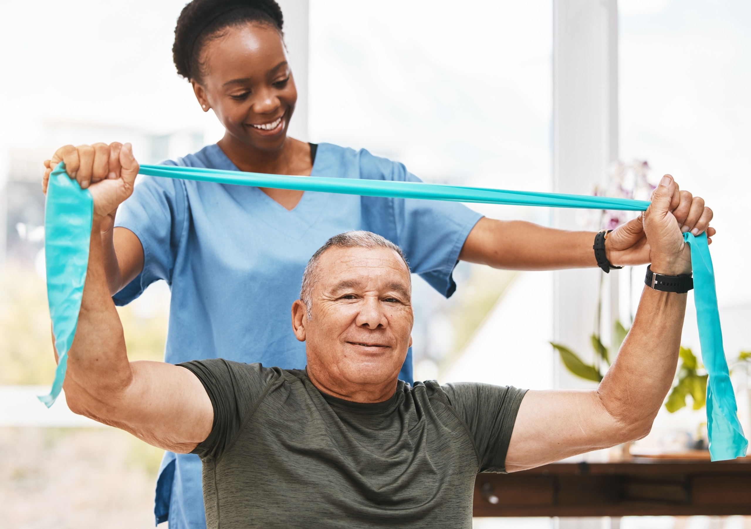 African-American professional helping an older man use an exercise band