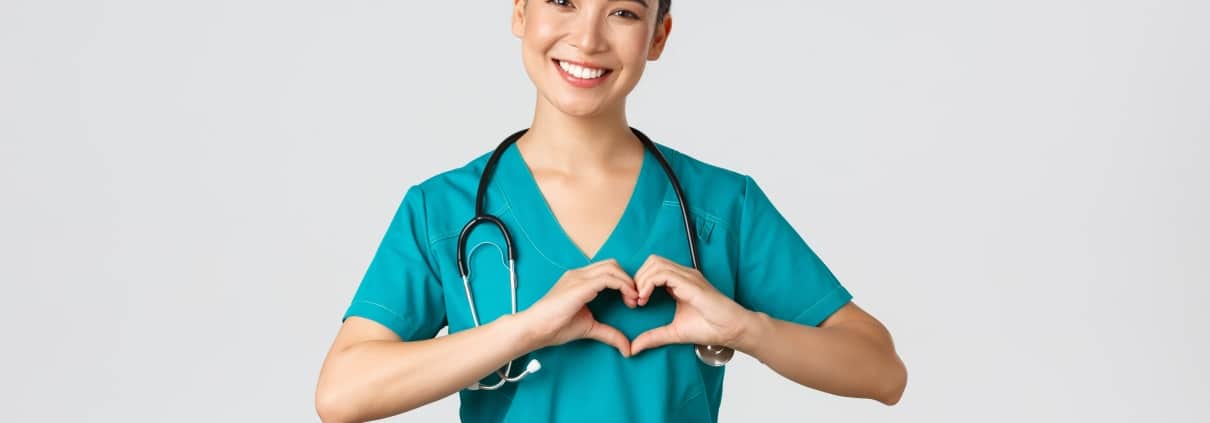 Smiling Asian nurse forming a heart with her hands
