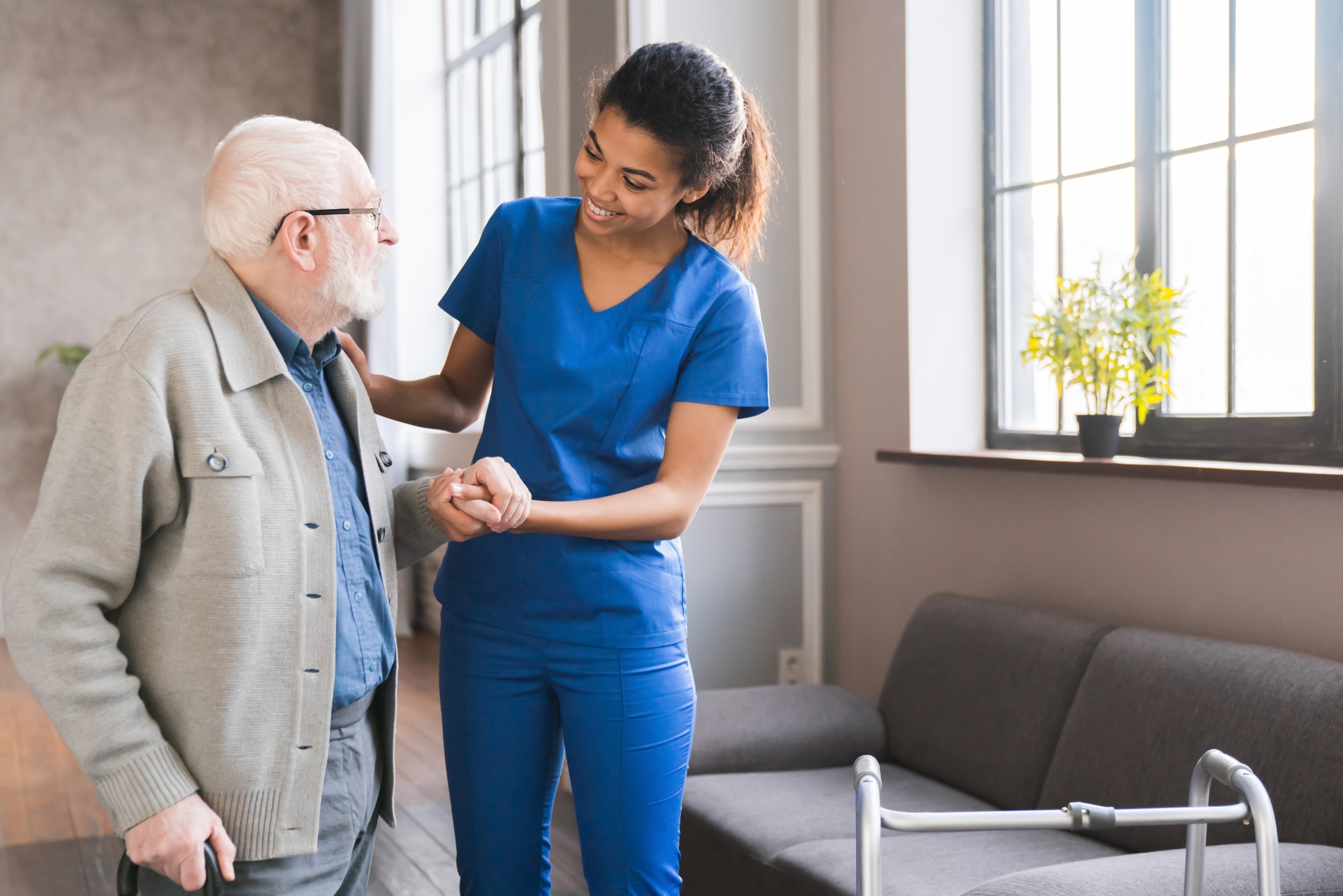 African-American nurse helping an elderly man walk