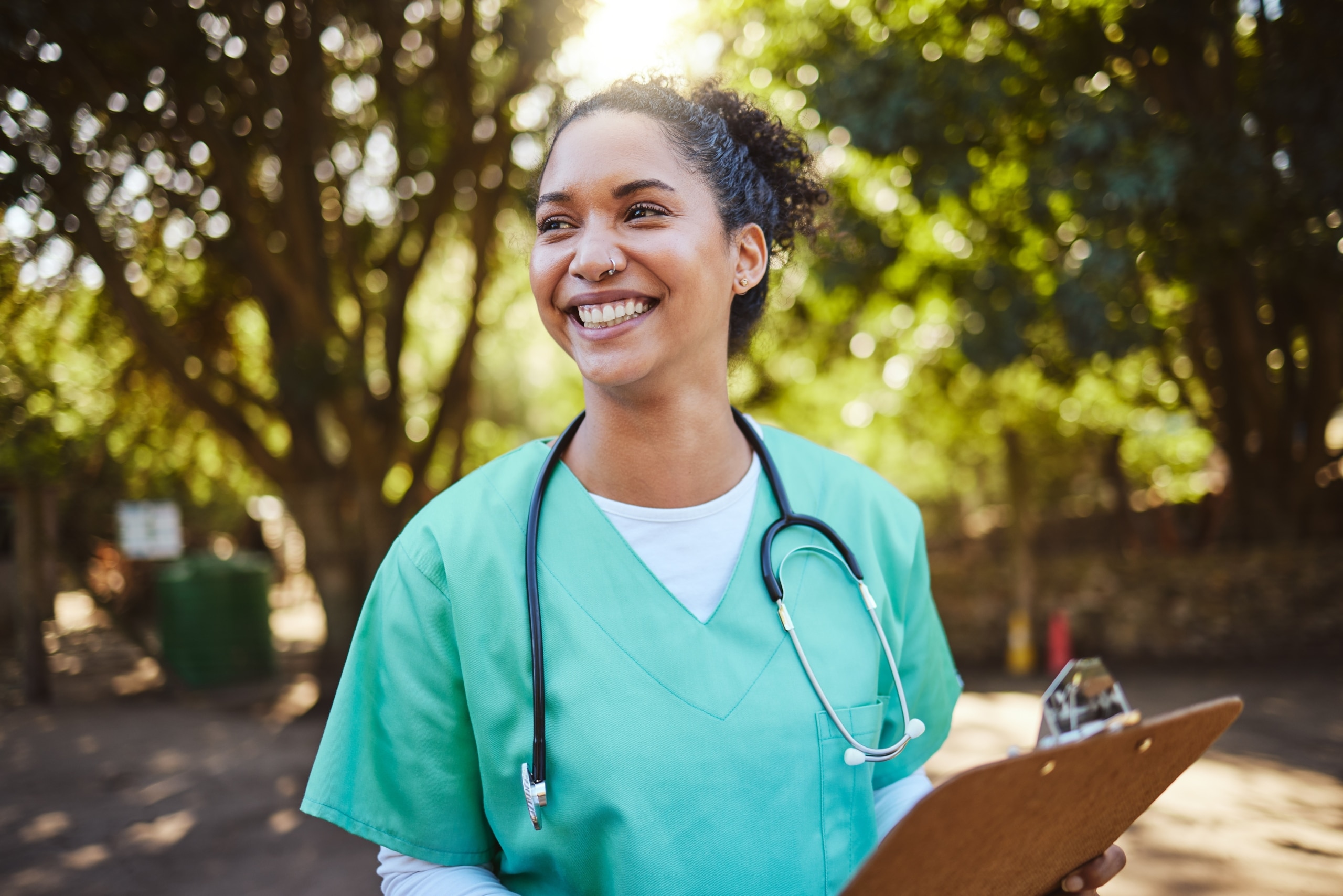 African-American nurse smiling outside with a clipboard
