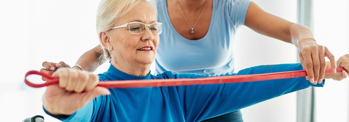 African-American medical professional helping a woman use an exercise band