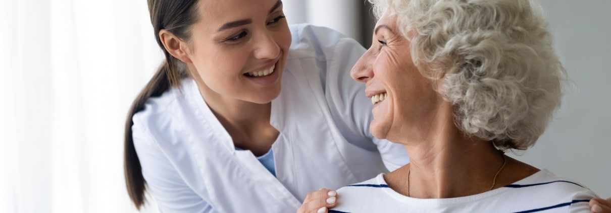 Elderly woman smiling at a young nurse over her shoulder