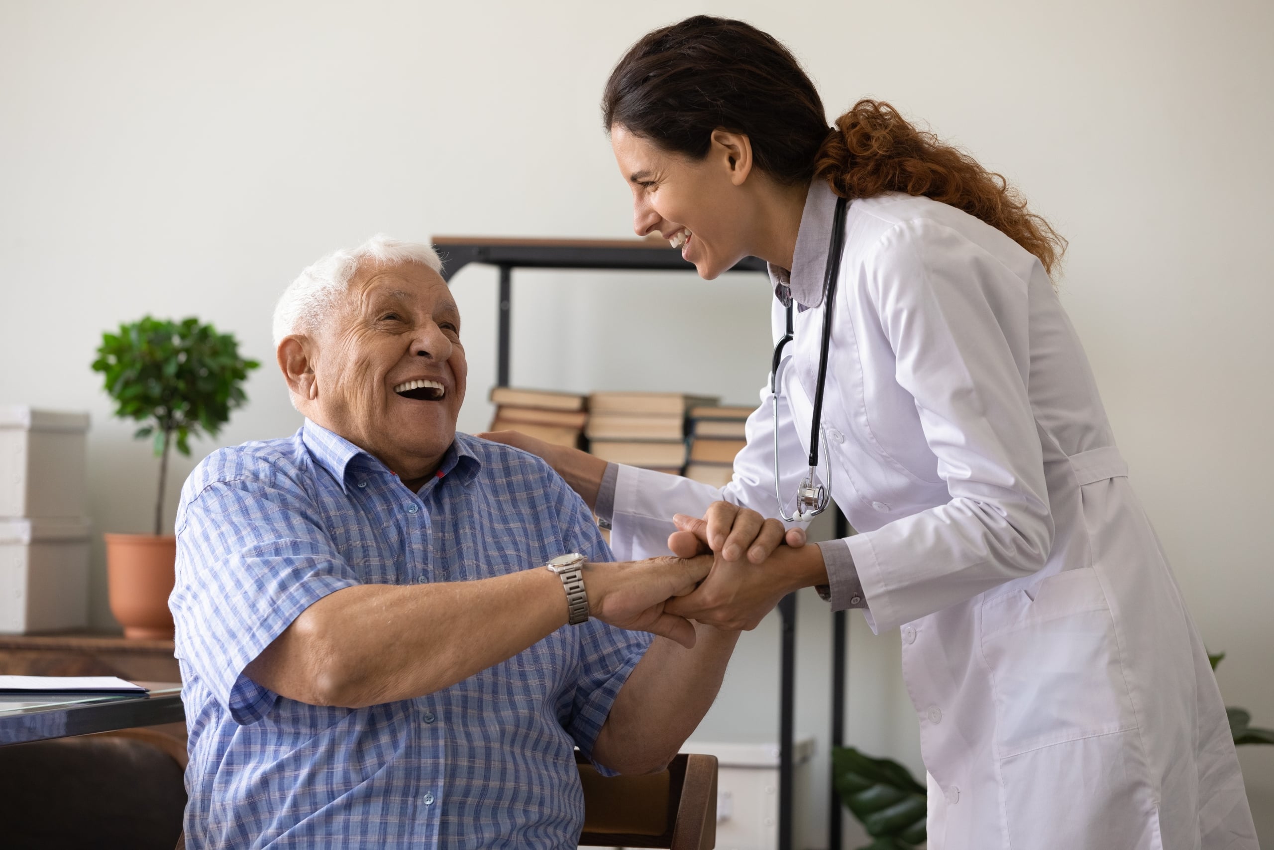 Elderly man laughing with a smiling young nurse