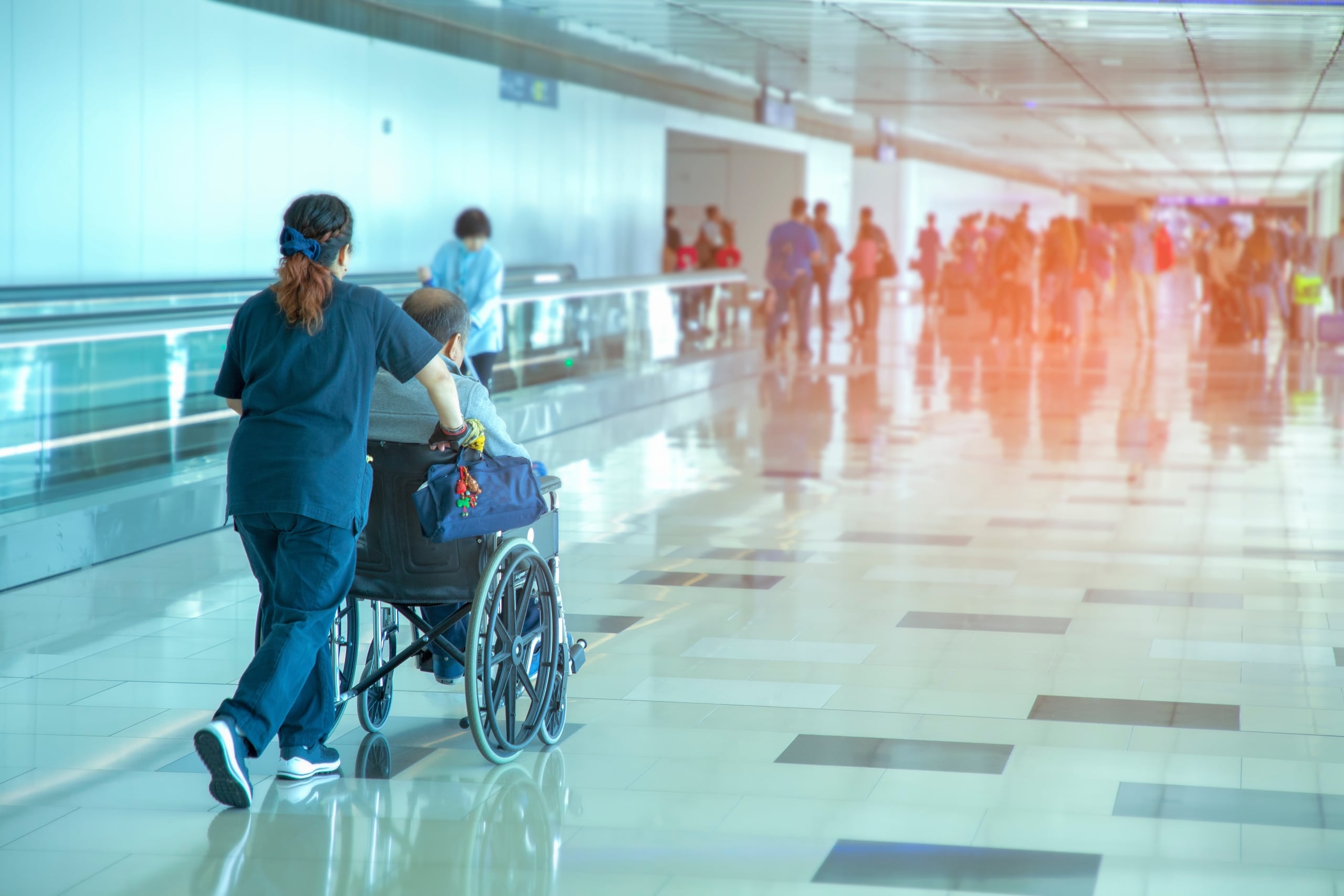 Nurse transporting a patient in a wheelchair through an airport