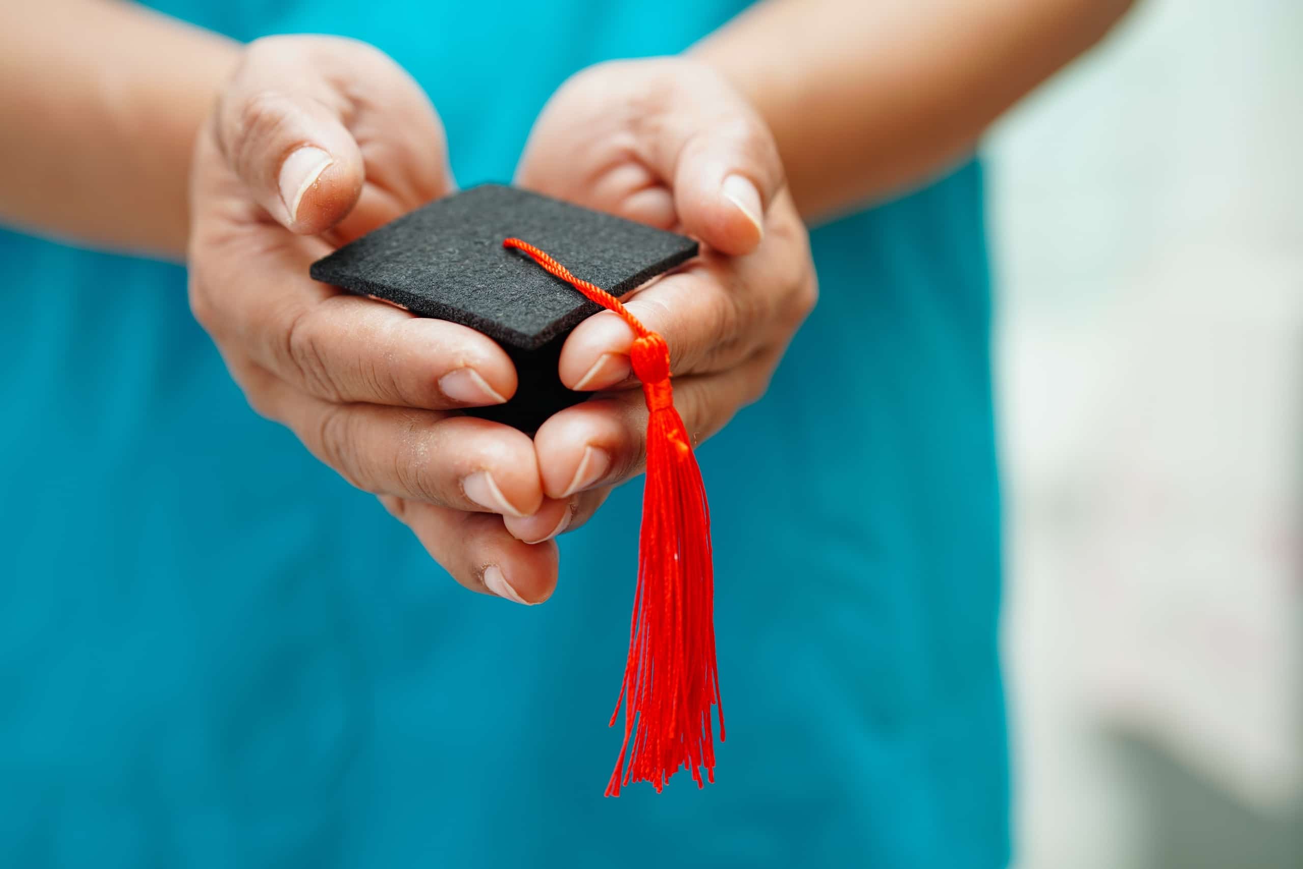 Close up of a nurse holding a miniature graduation cap
