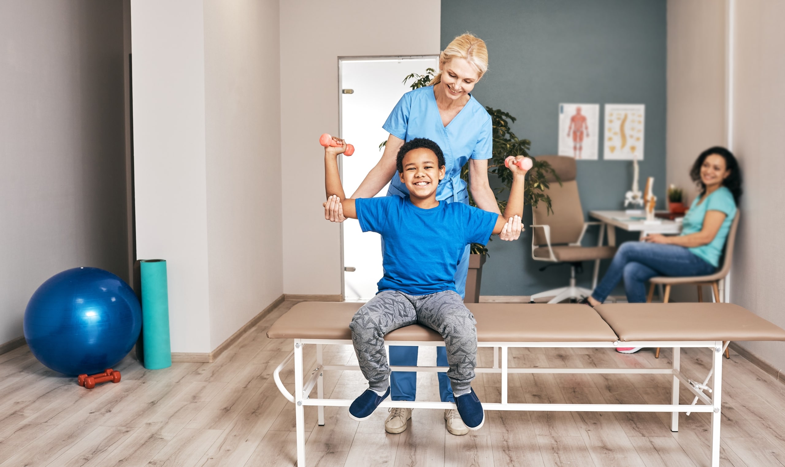 Physical therapy professional helping a young boy lift weights