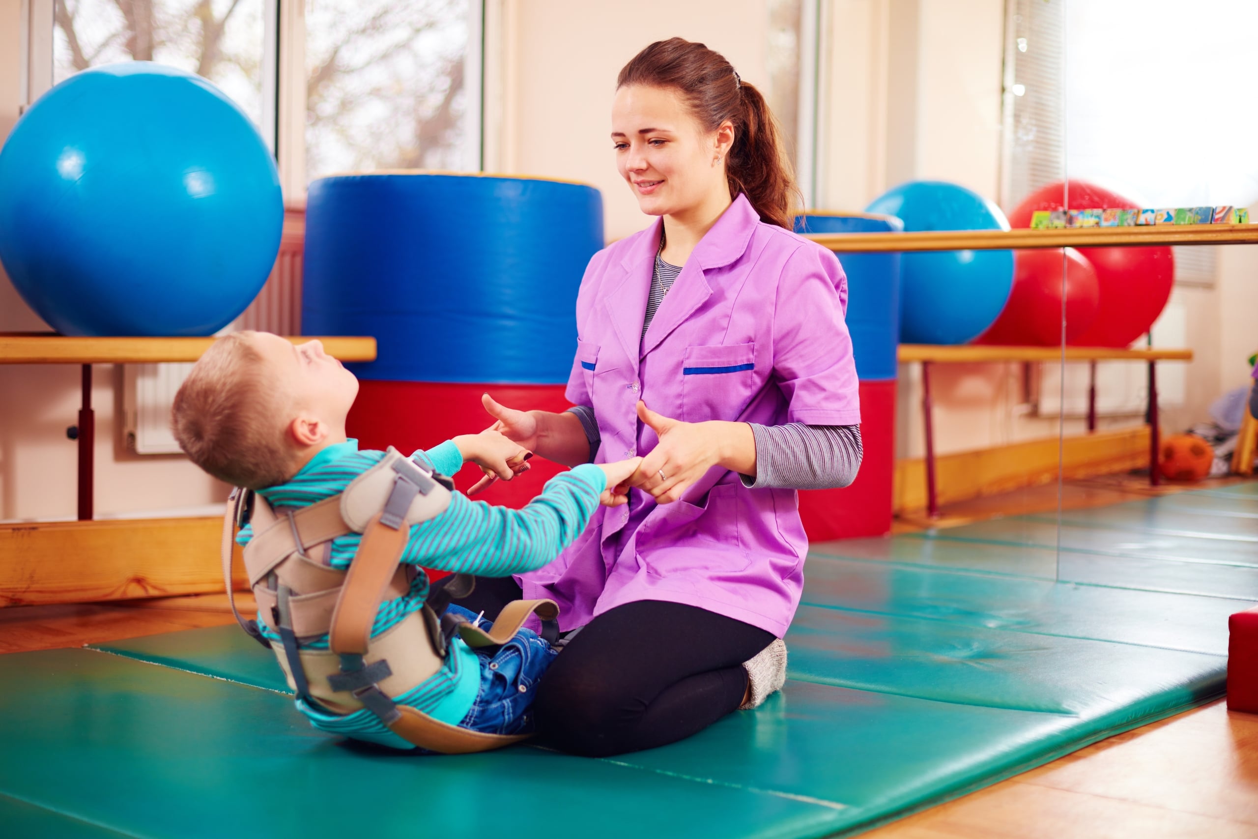 Physical therapy professional working with a boy who has cerebral palsy