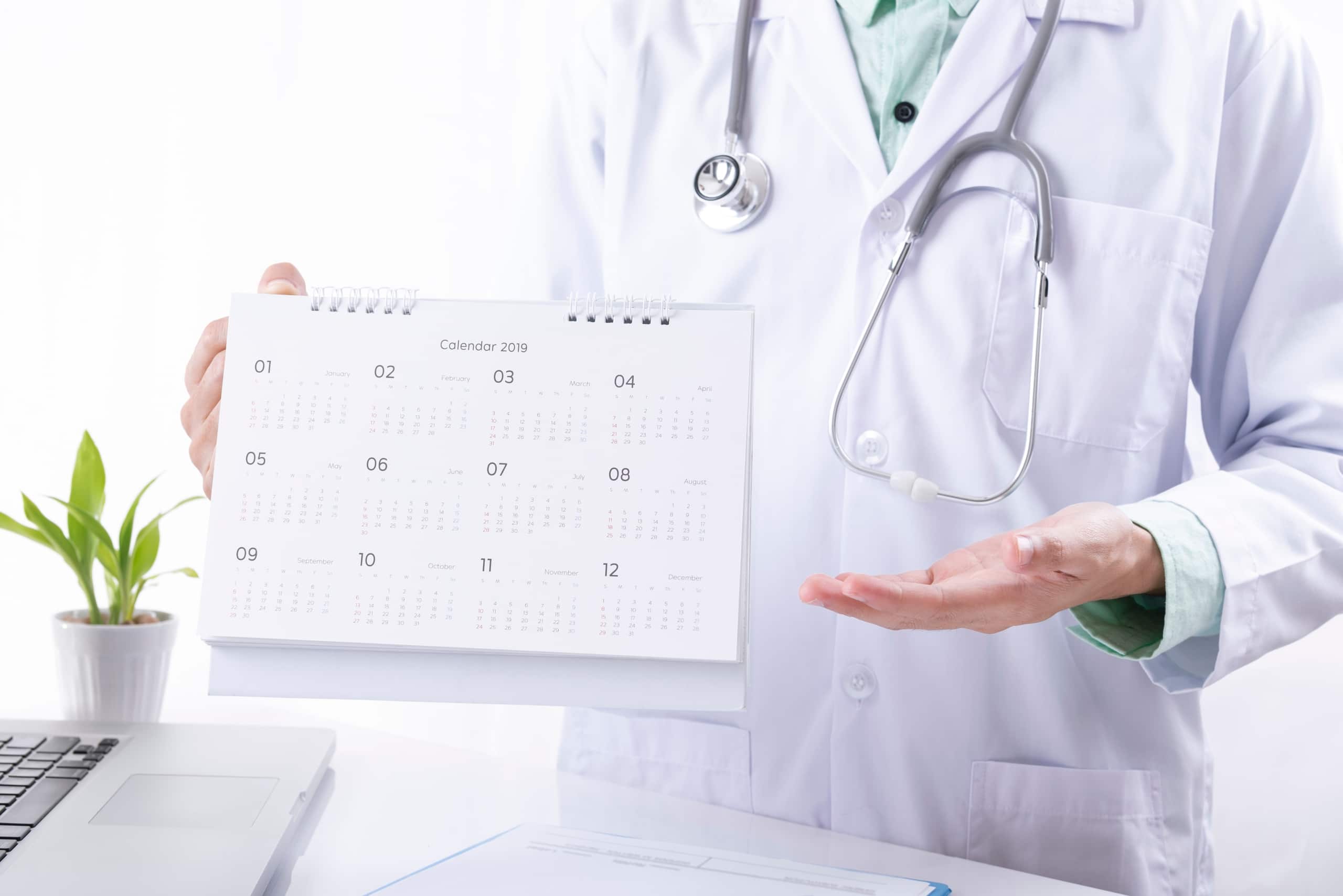 Close up of a medical professional holding a desk calendar