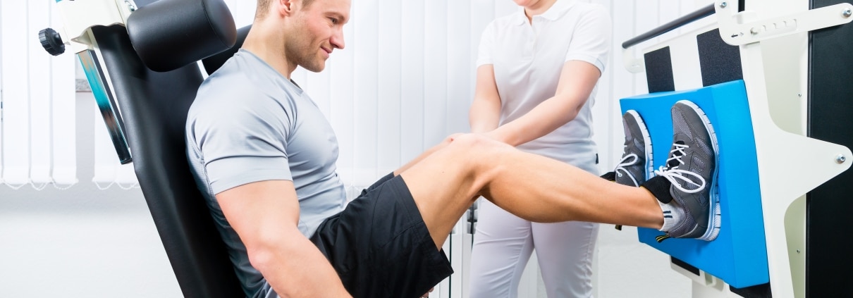 Physical therapy professional helping a male athlete use equipment