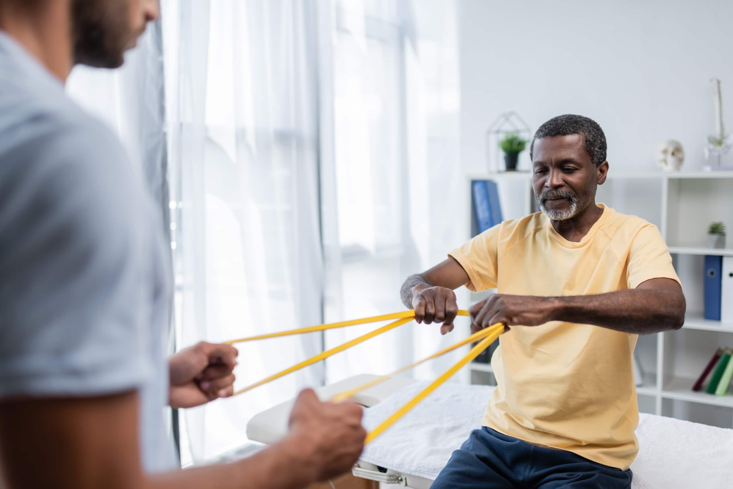 African-American man using an exercise band in physical therapy