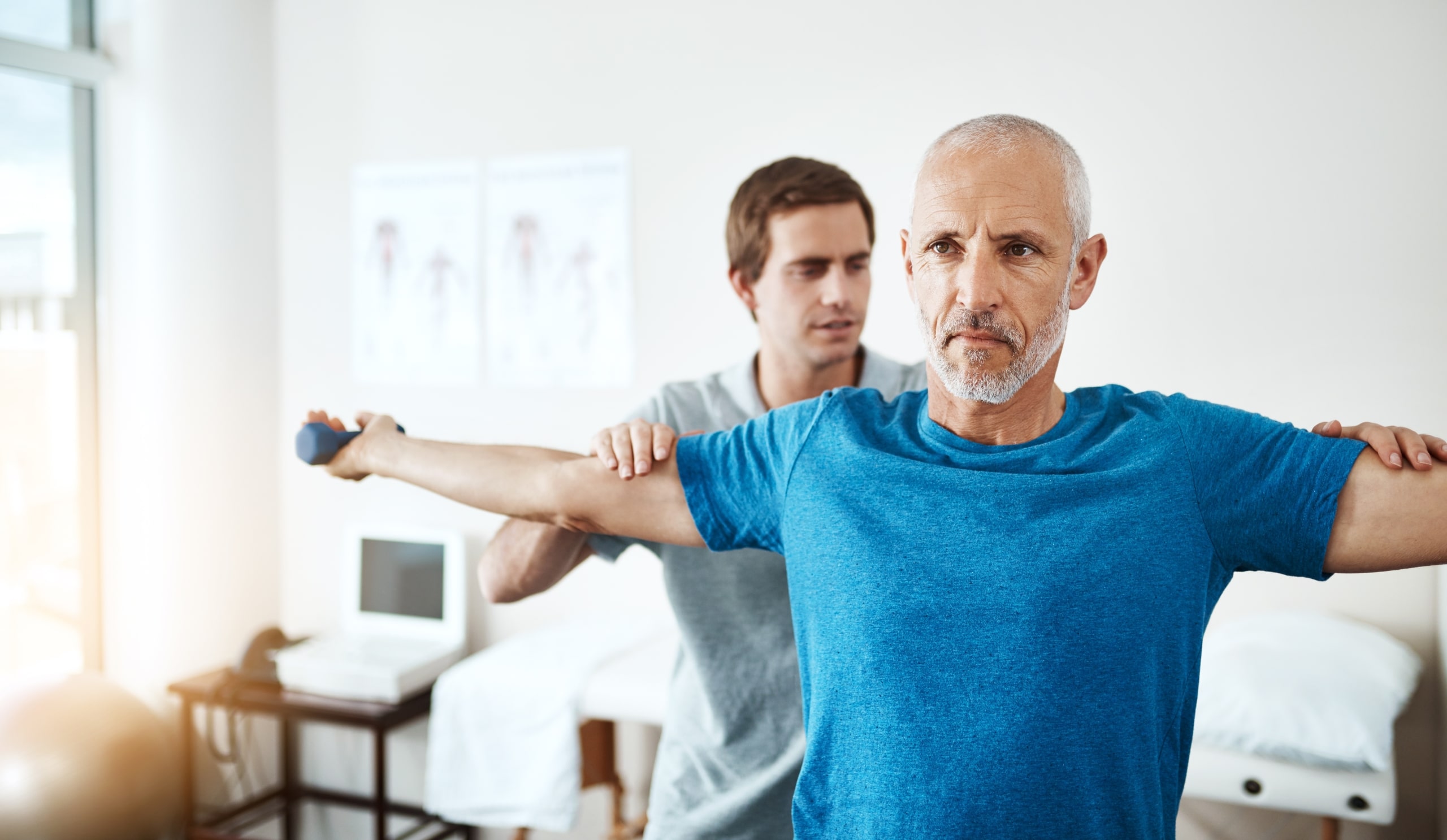 Older man lifting hand weights in physical therapy