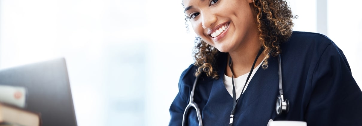 Smiling African-American nurse typing on a laptop
