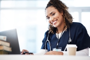 Smiling African-American nurse typing on a laptop