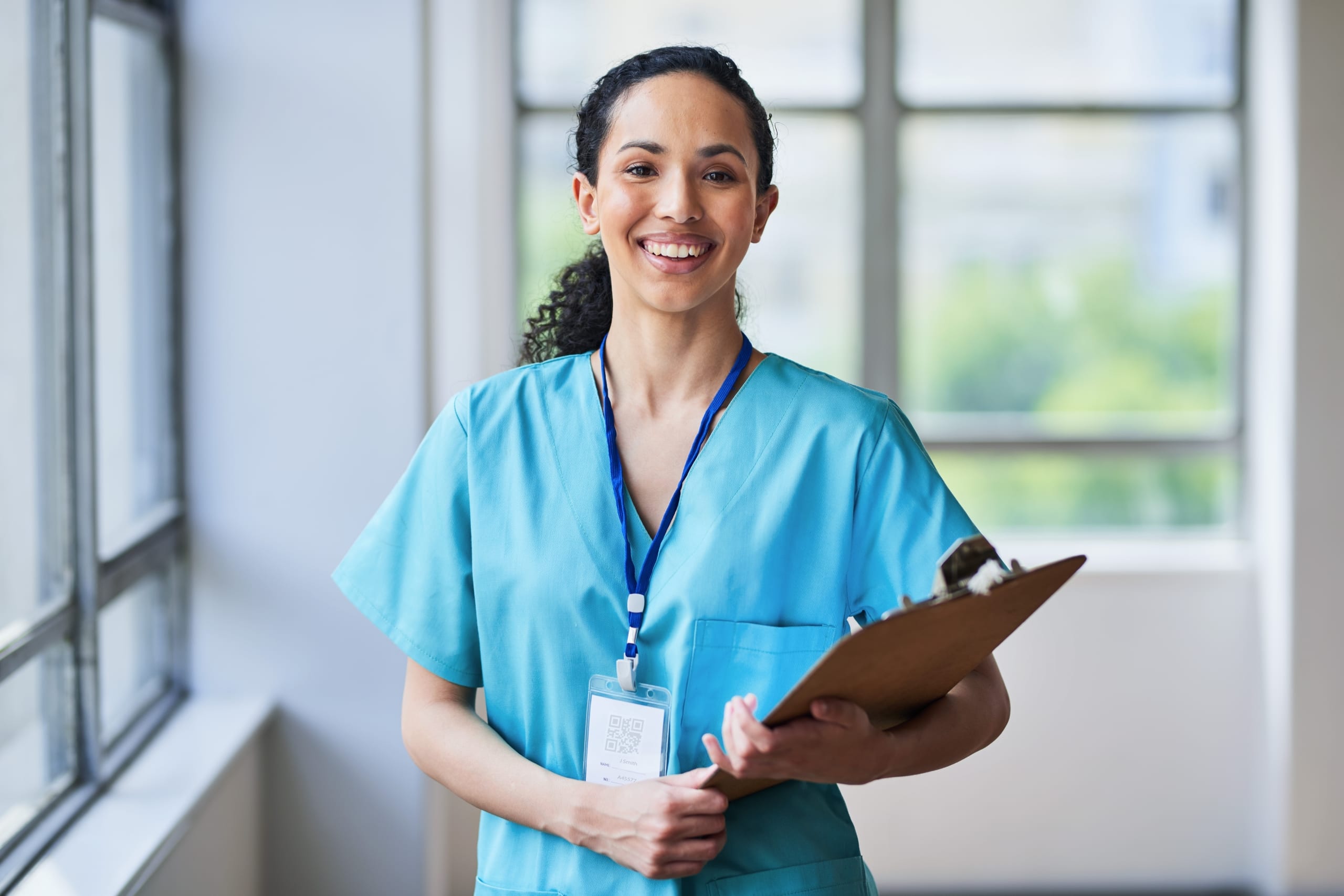 Smiling medical professional in scrubs with a clipboard