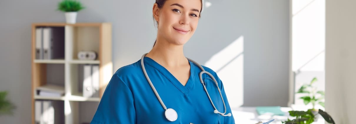 Happy nurse smiling as she writes on a clipboard