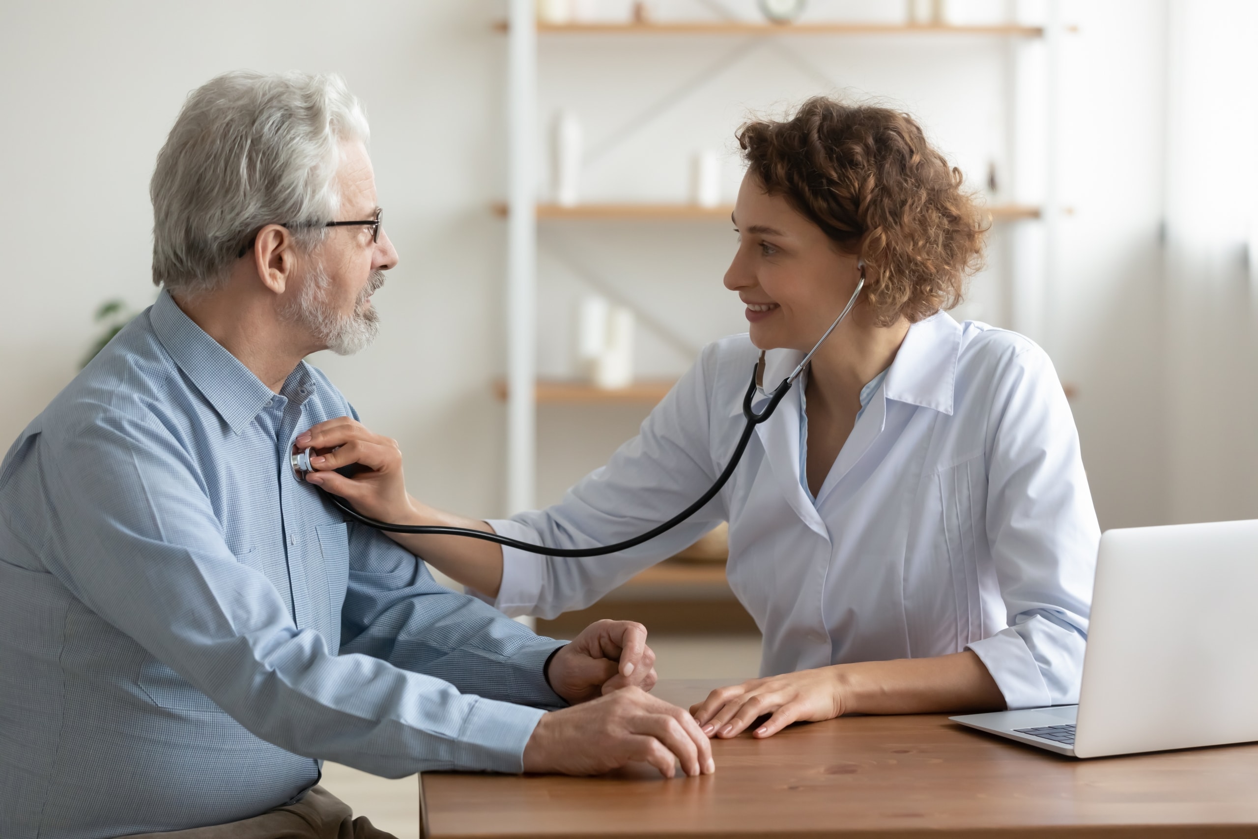 Female medical professional using a stethoscope with an older patient