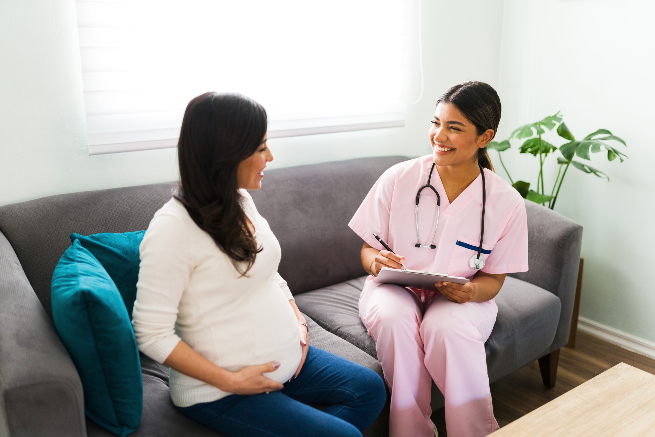 Nurse midwife speaking with a pregnant patient on a couch