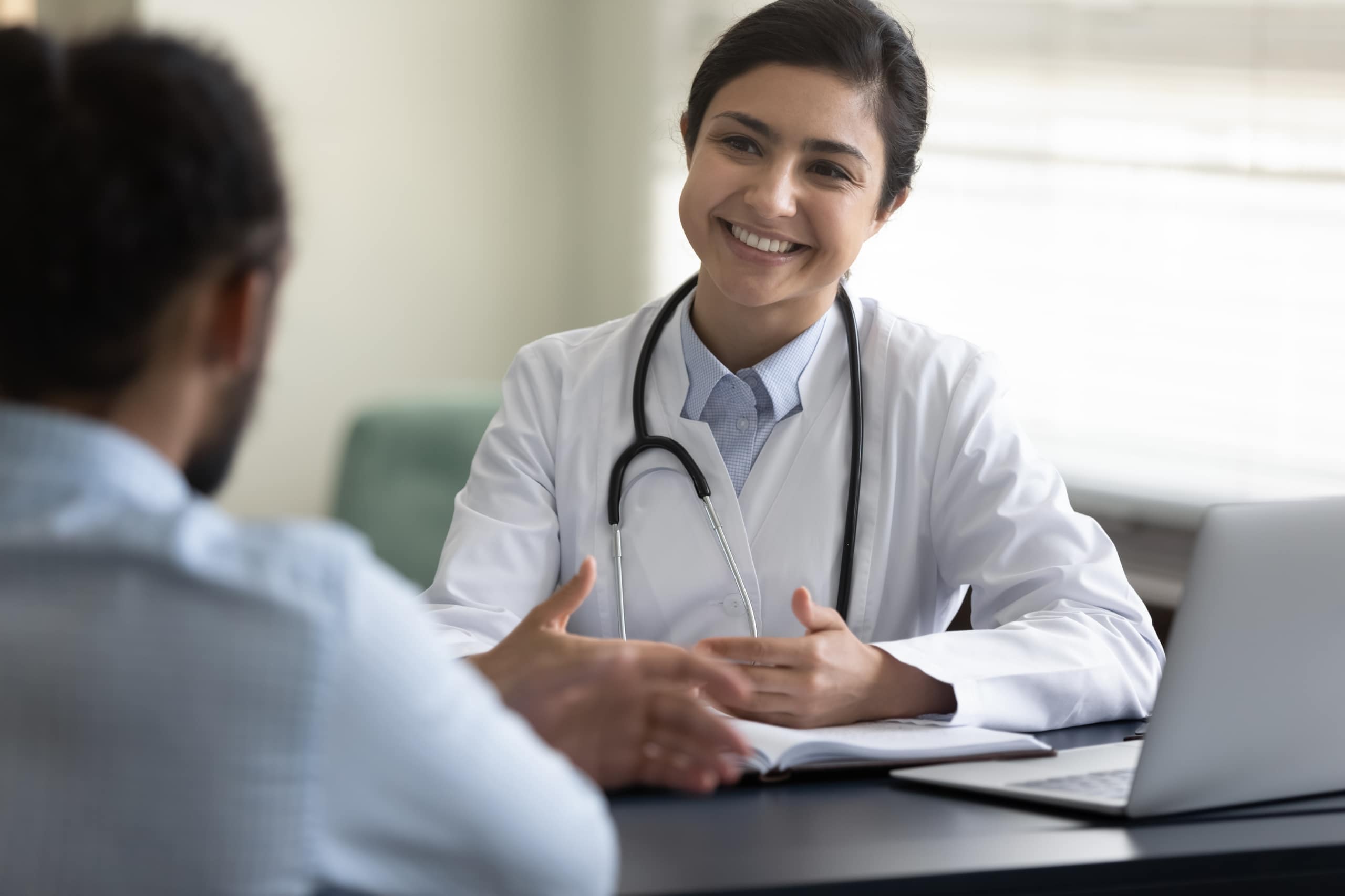 Indian medical professional smiling at a man across her desk