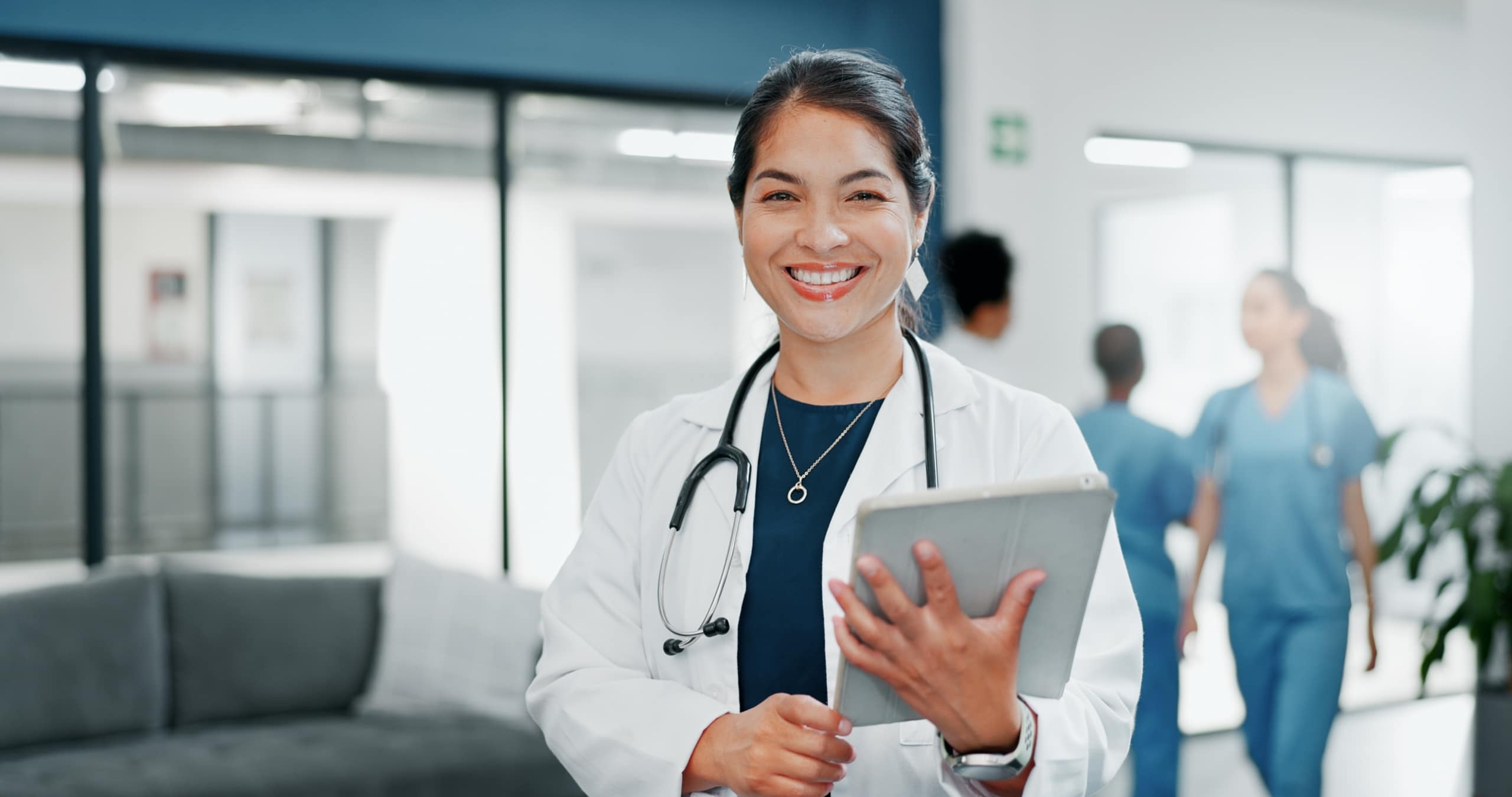 Happy medical professional holding a tablet in a hospital