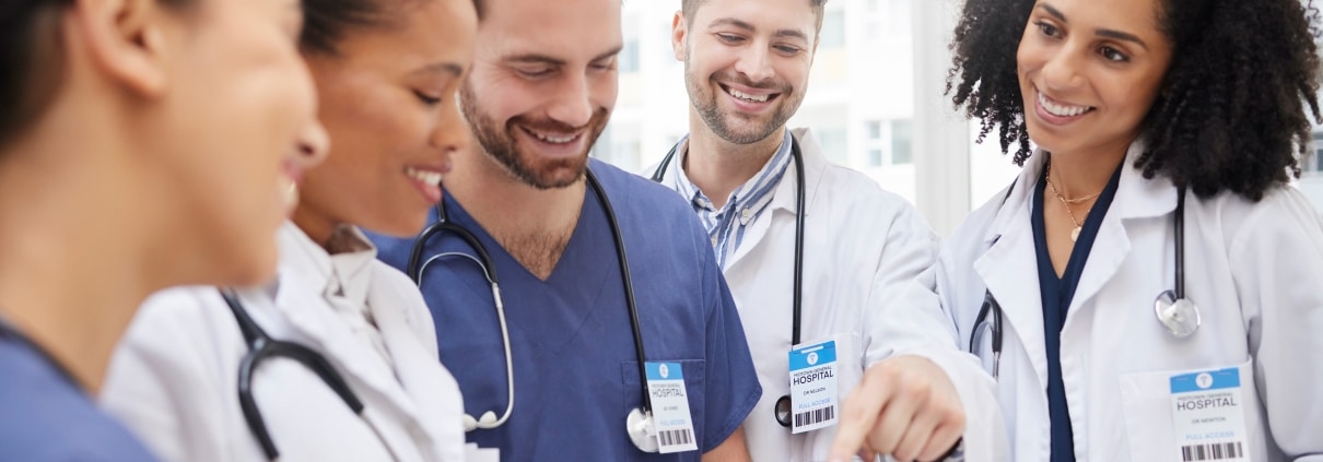 Group of medical professionals smiling and looking at a tablet