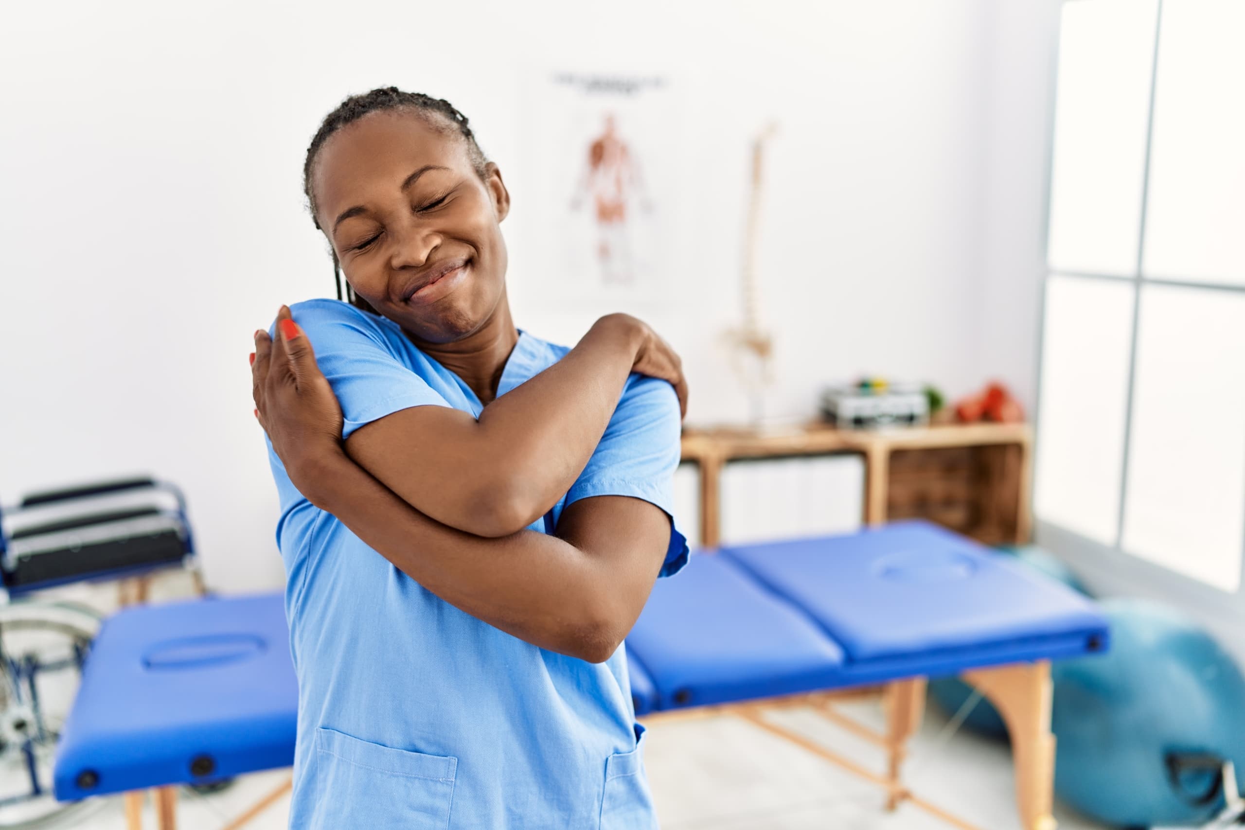 African-American physical therapy professional hugging herself