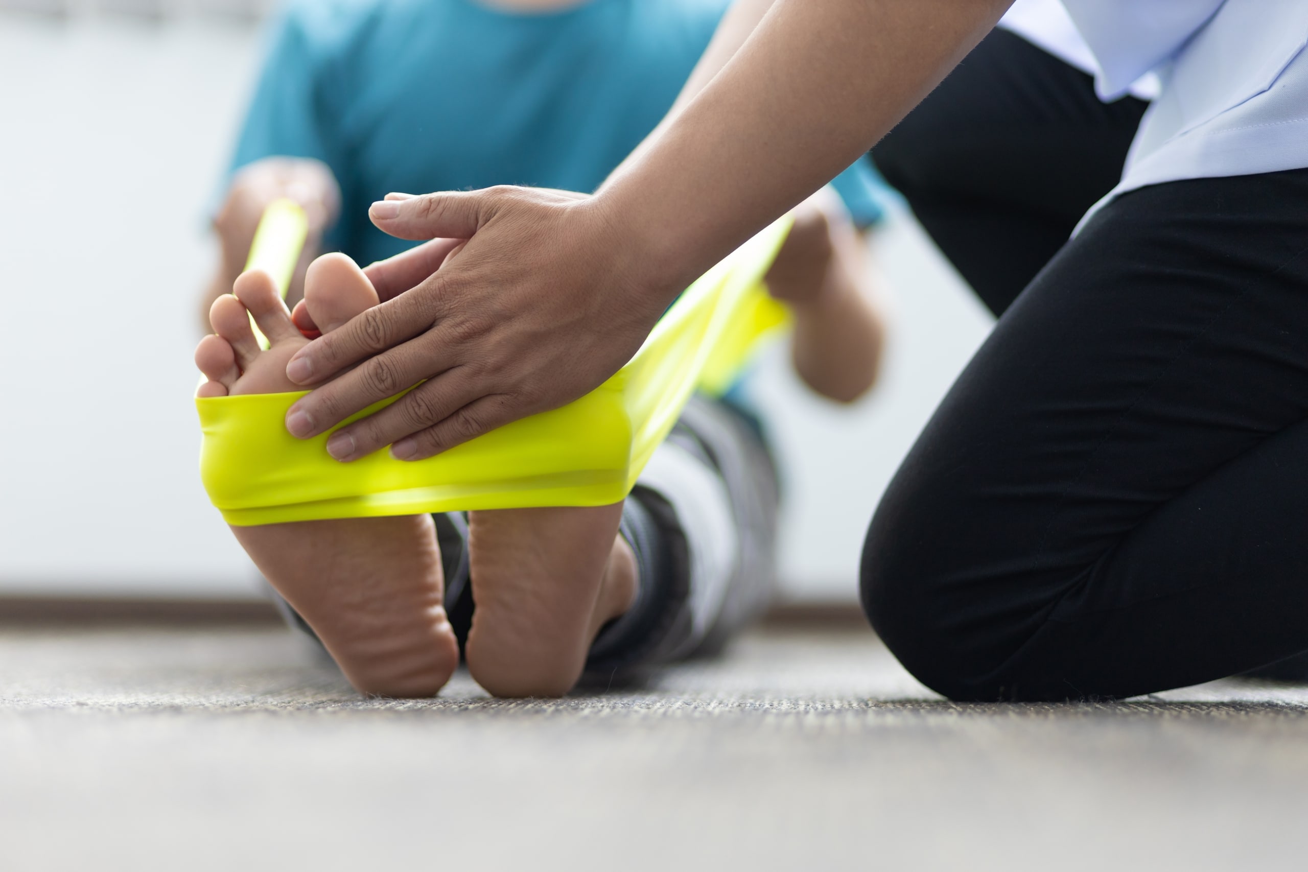 Physical therapist assistant helping a patient use an exercise band