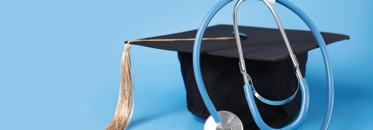 Graduation cap and a stethoscope against a light blue backdrop
