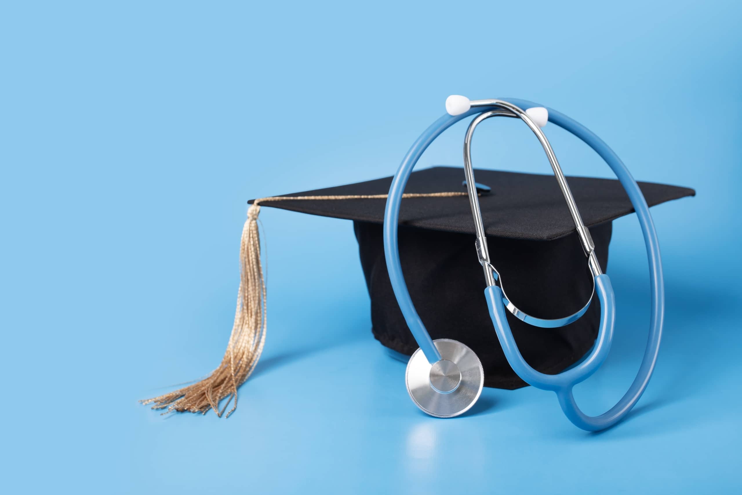 Graduation cap and a stethoscope against a light blue backdrop