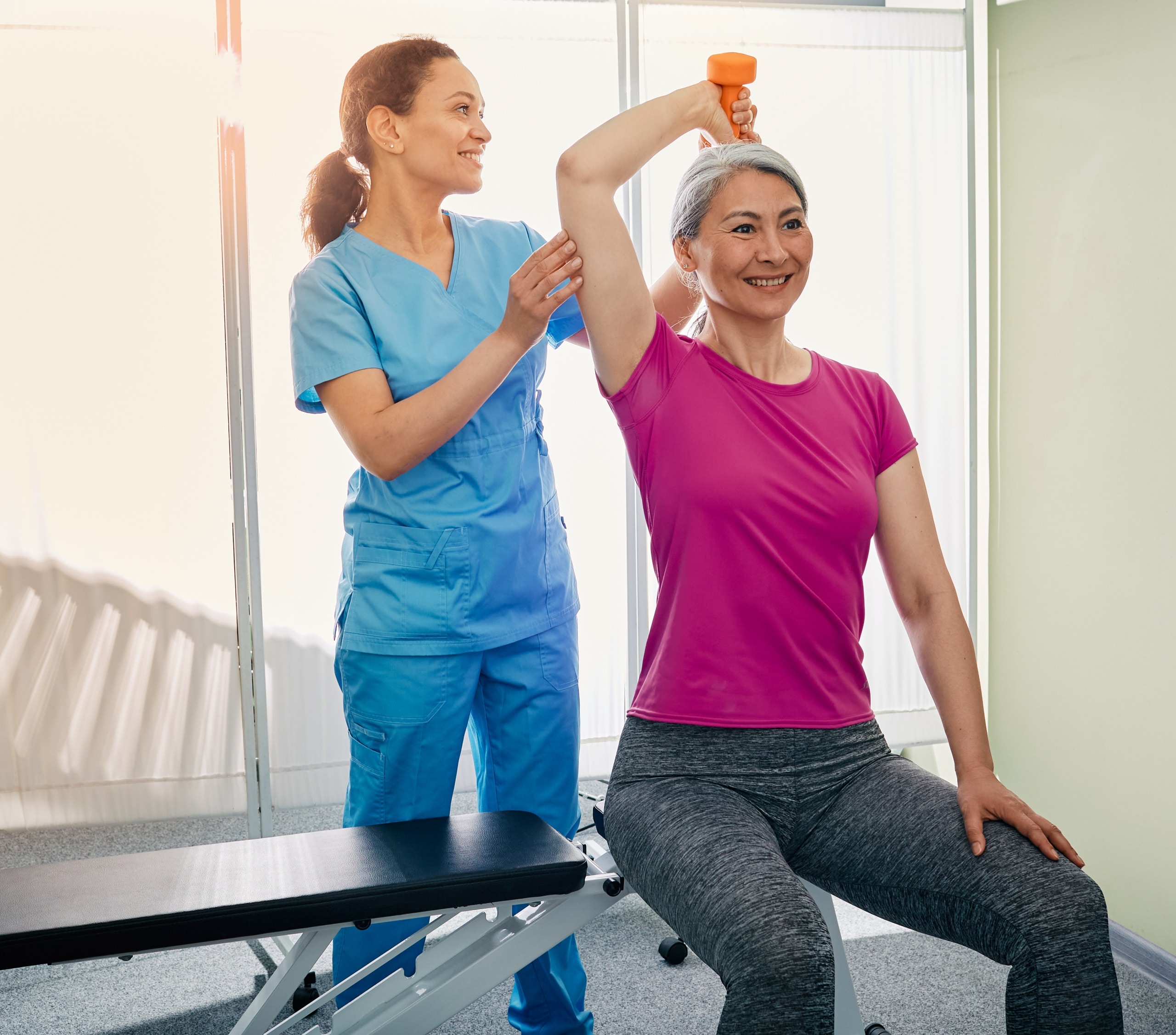 Physical therapy professional helping an older woman use weights