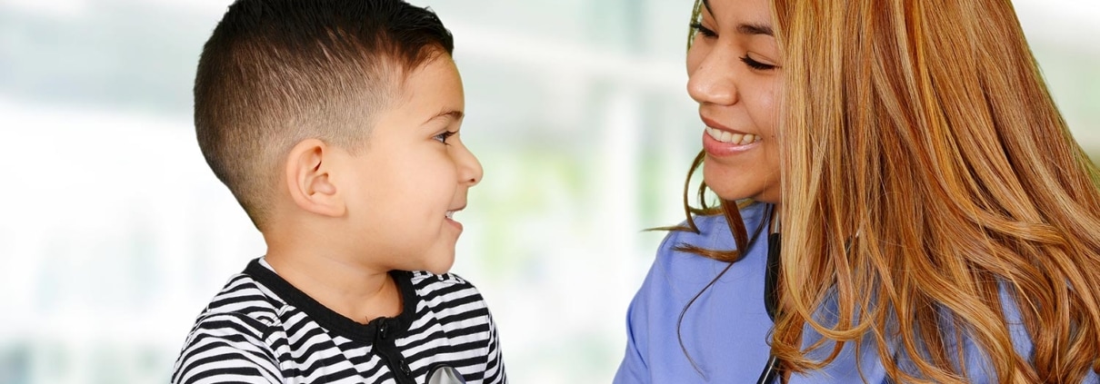 Female Hispanic nurse listening to a child's heartbeat